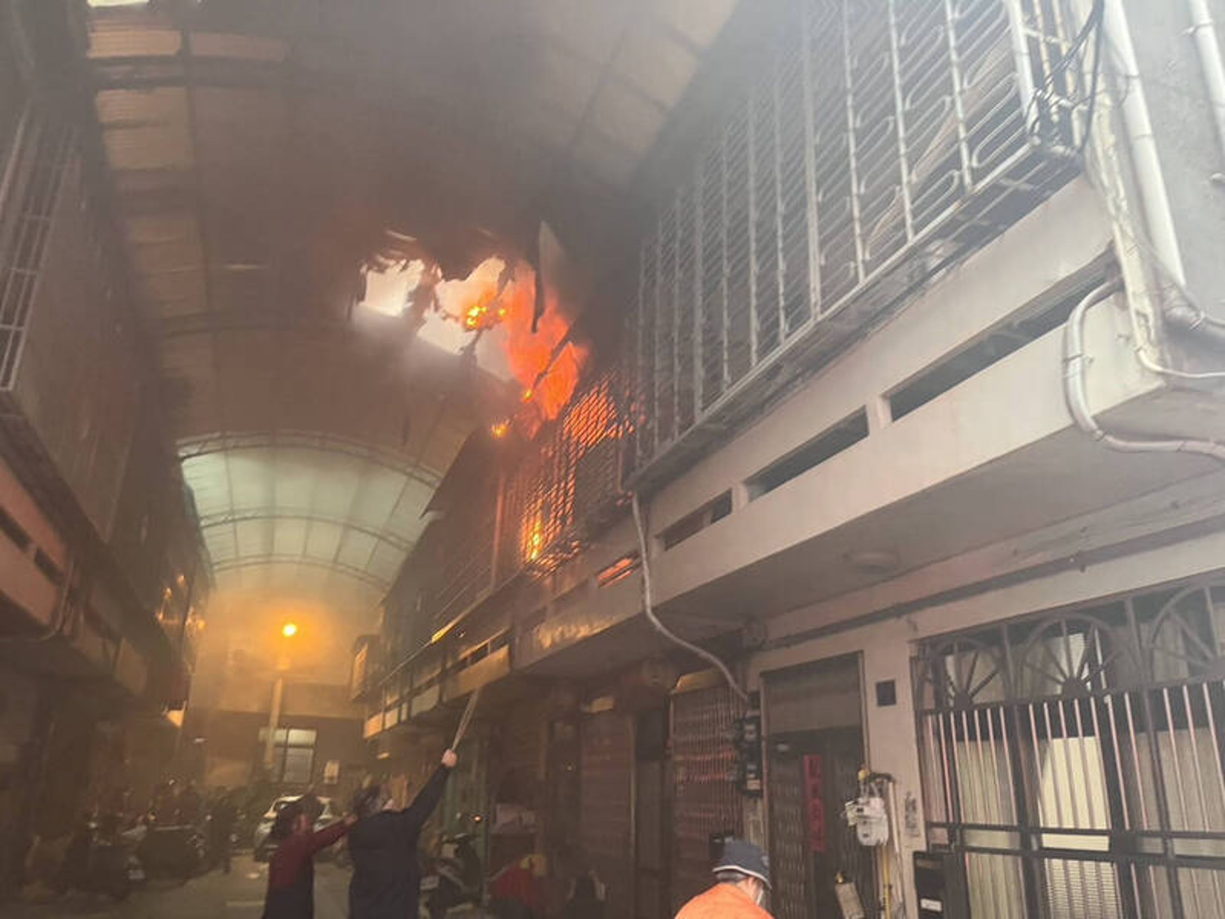 新竹縣竹北市中山路住宅火警,2樓竄出火舌,消防人員救出受困老翁後,全力噴水降溫、灌救。(消防局提供)