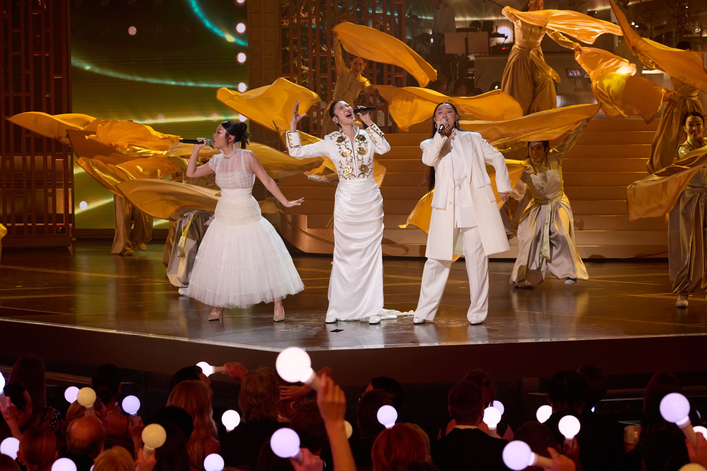 「HUNTR/X」幕後代唱Rei Ami（左起）、EJAE、Audrey Nuna登上奧斯卡舞台，現場表演〈Golden〉，觀眾還拿手燈應援。（Trae Patton攝／The Academy©A.M.P.A.S.）
