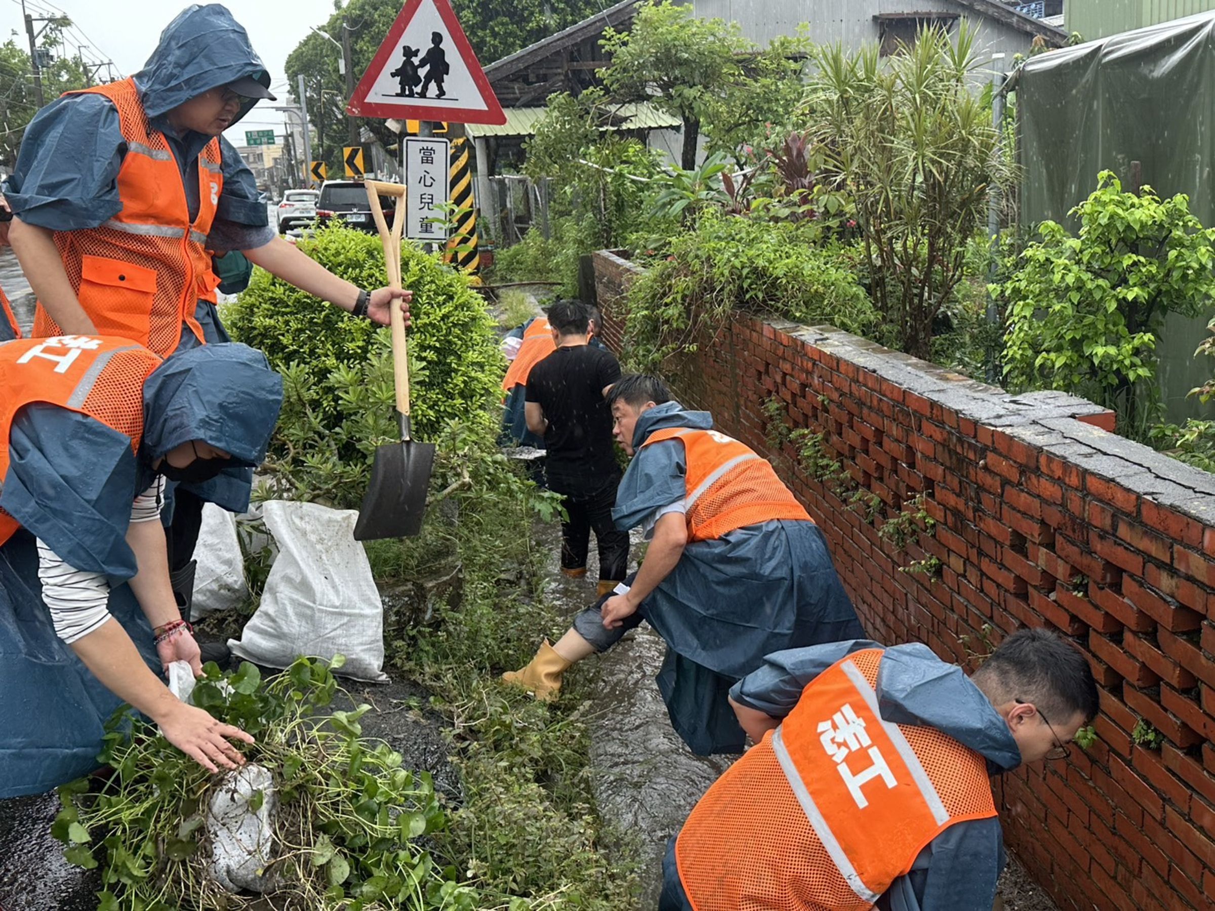 何博文(中)親自跳下水溝救災清淤,但遭質疑擺拍。(民進黨提供)