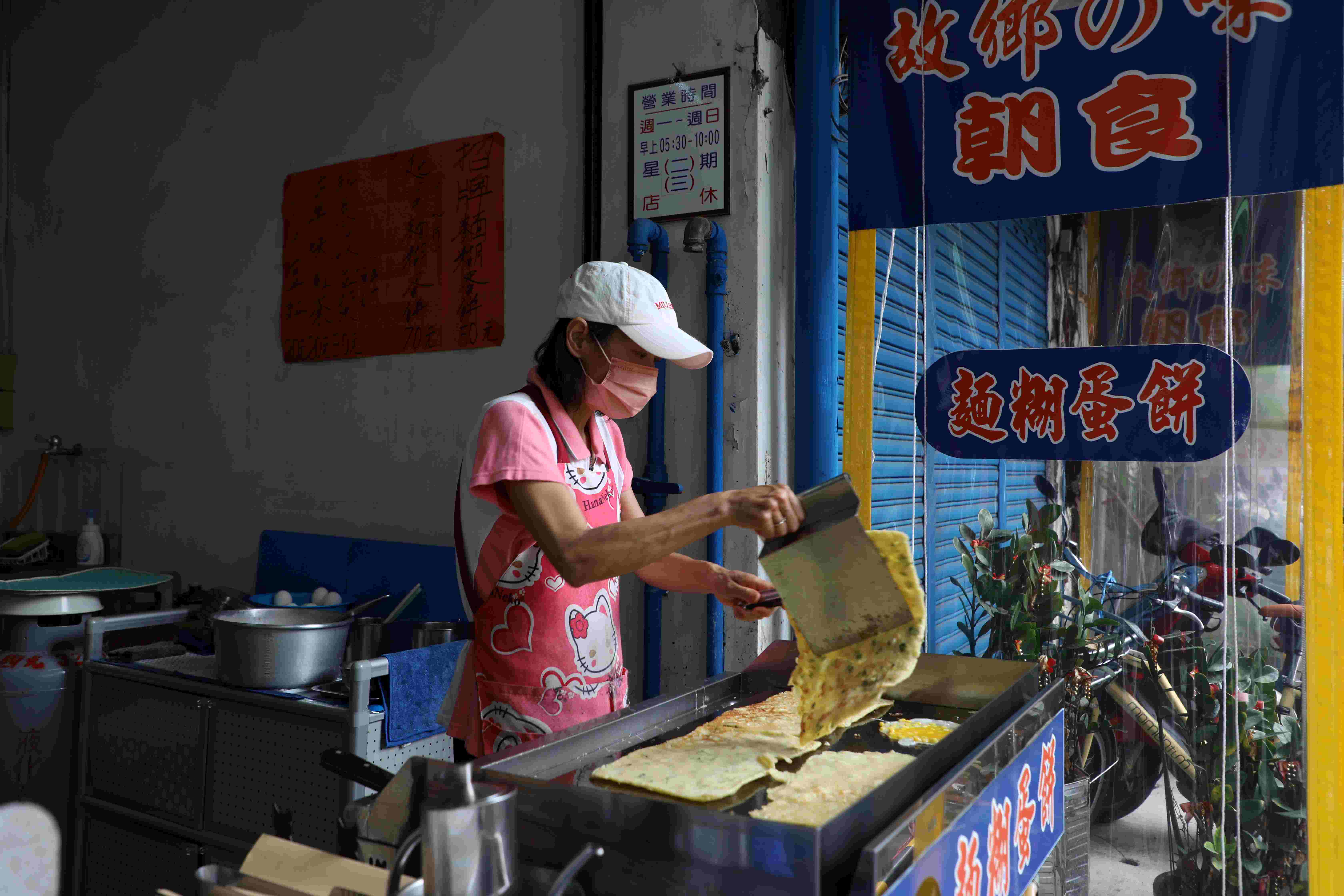 「故鄉味麵糊蛋餅」老闆娘雙手不停地在煎台上倒粉漿、煎蛋餅。