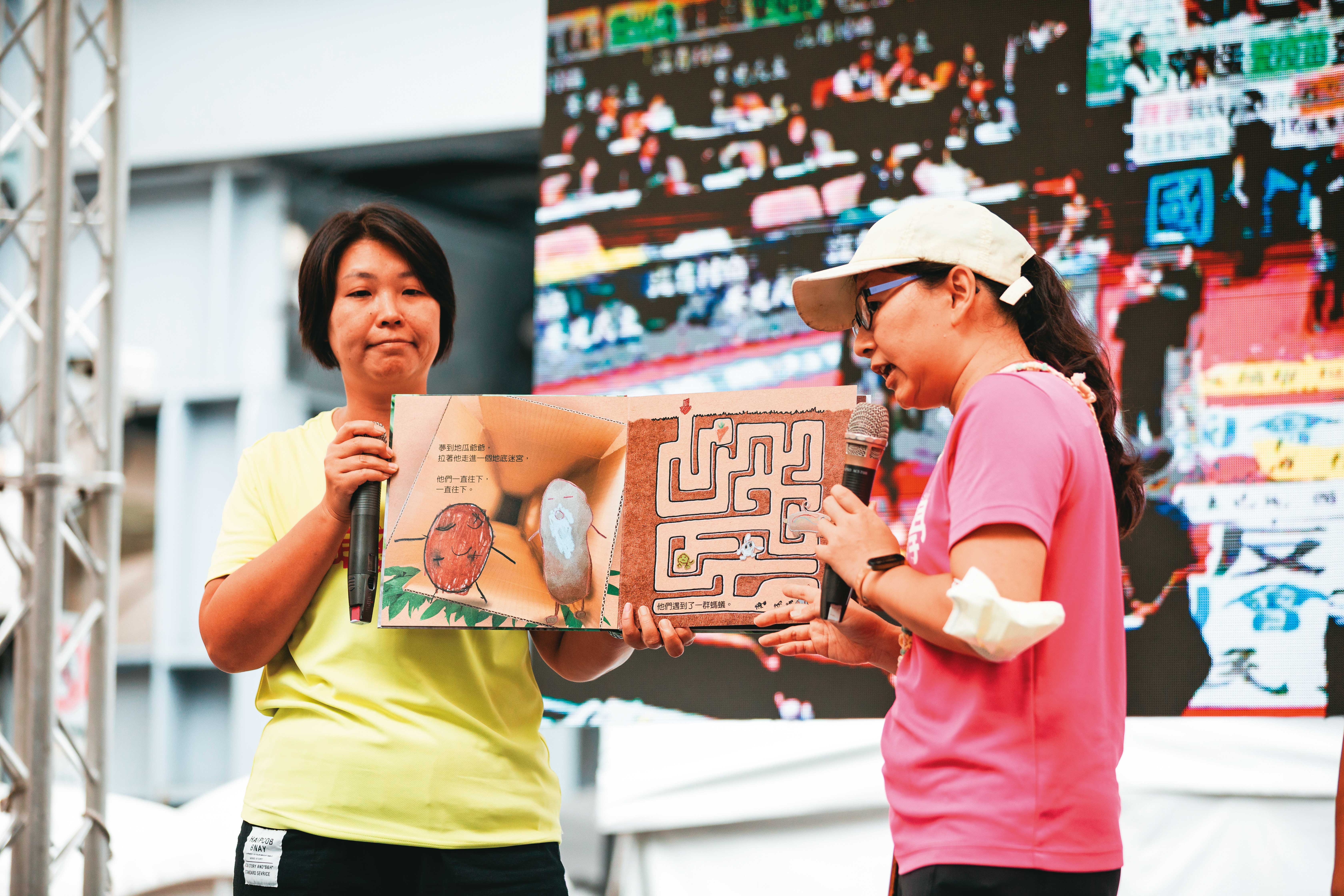 台灣親子共學教育促進會在舞台上朗讀繪本，手上拿的是親子共同以「竹科三期開發案」為本創作、談程序正義議題的《地瓜打嗝了》。