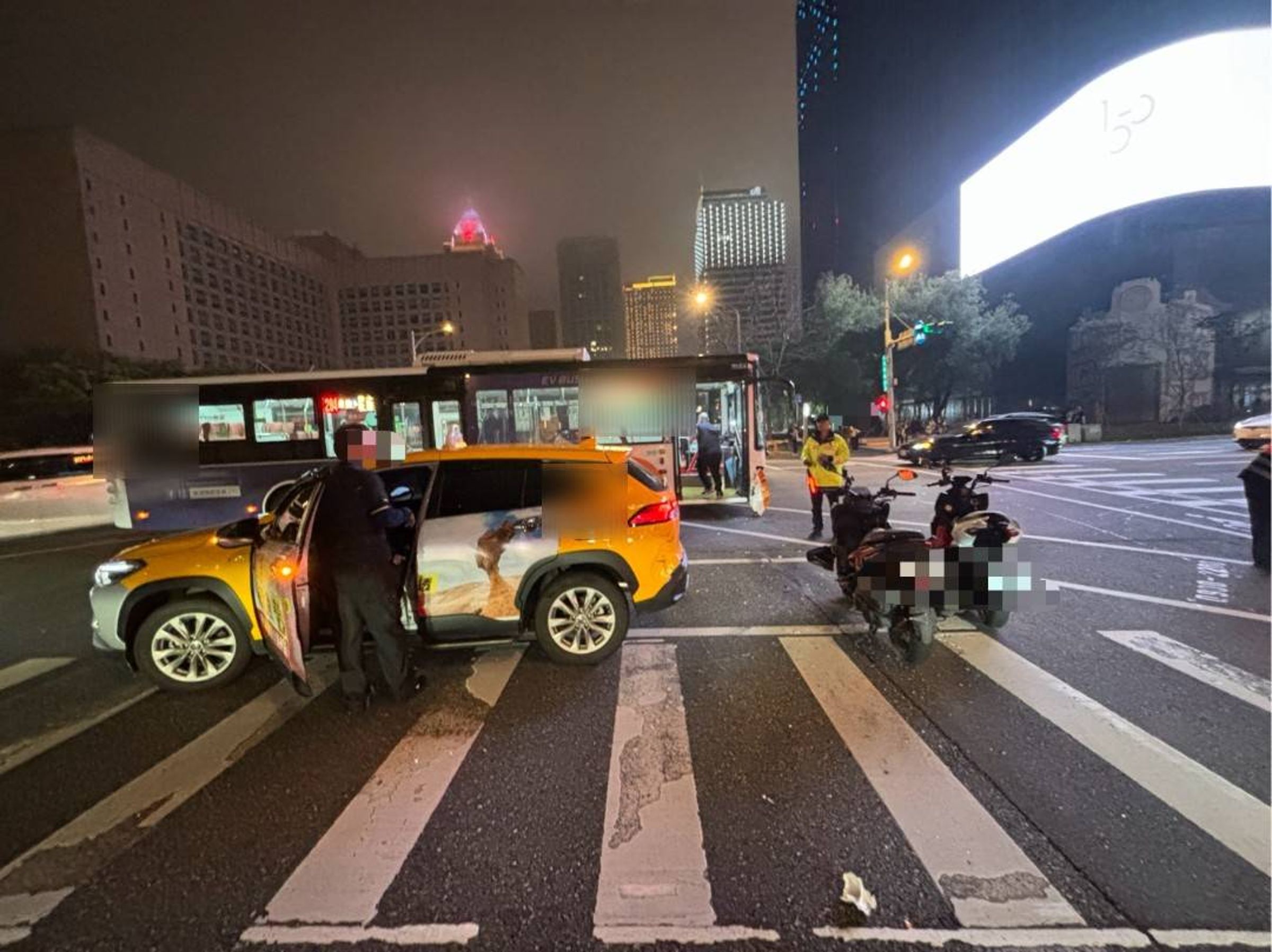 信義商圈昨晚發生計程車與公車碰撞車禍,還波及待轉機車,造成2名騎士雙腳擦挫傷送醫。(翻攝畫面)