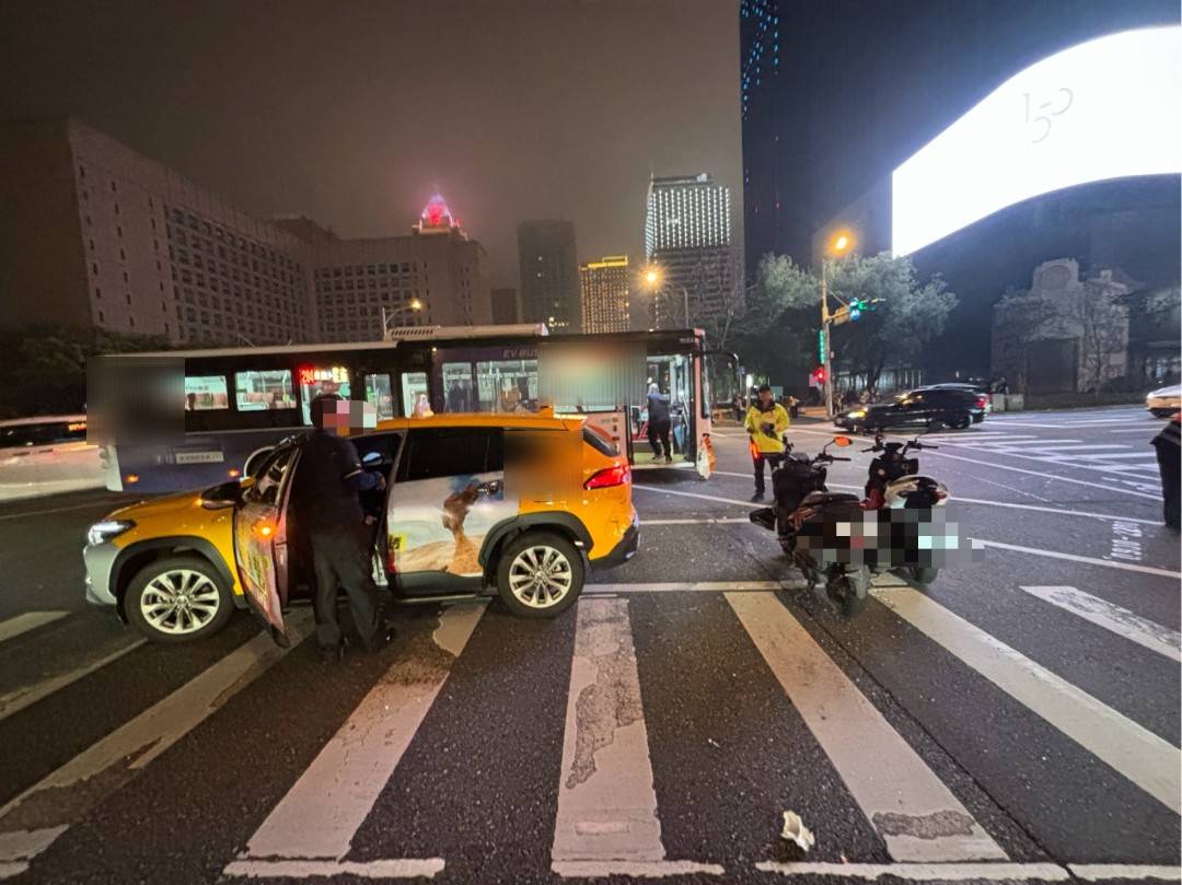 信義商圈昨晚發生計程車與公車碰撞車禍，還波及待轉機車，造成2名騎士雙腳擦挫傷送醫。（翻攝畫面）