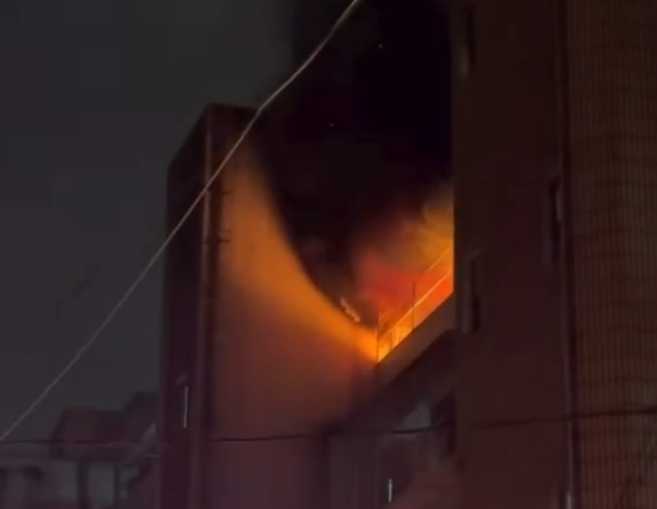 台北市信義區永吉路巷弄老舊公寓，今日凌晨竄出火舌，消防人員在陽台救出受困男子。（翻攝畫面）