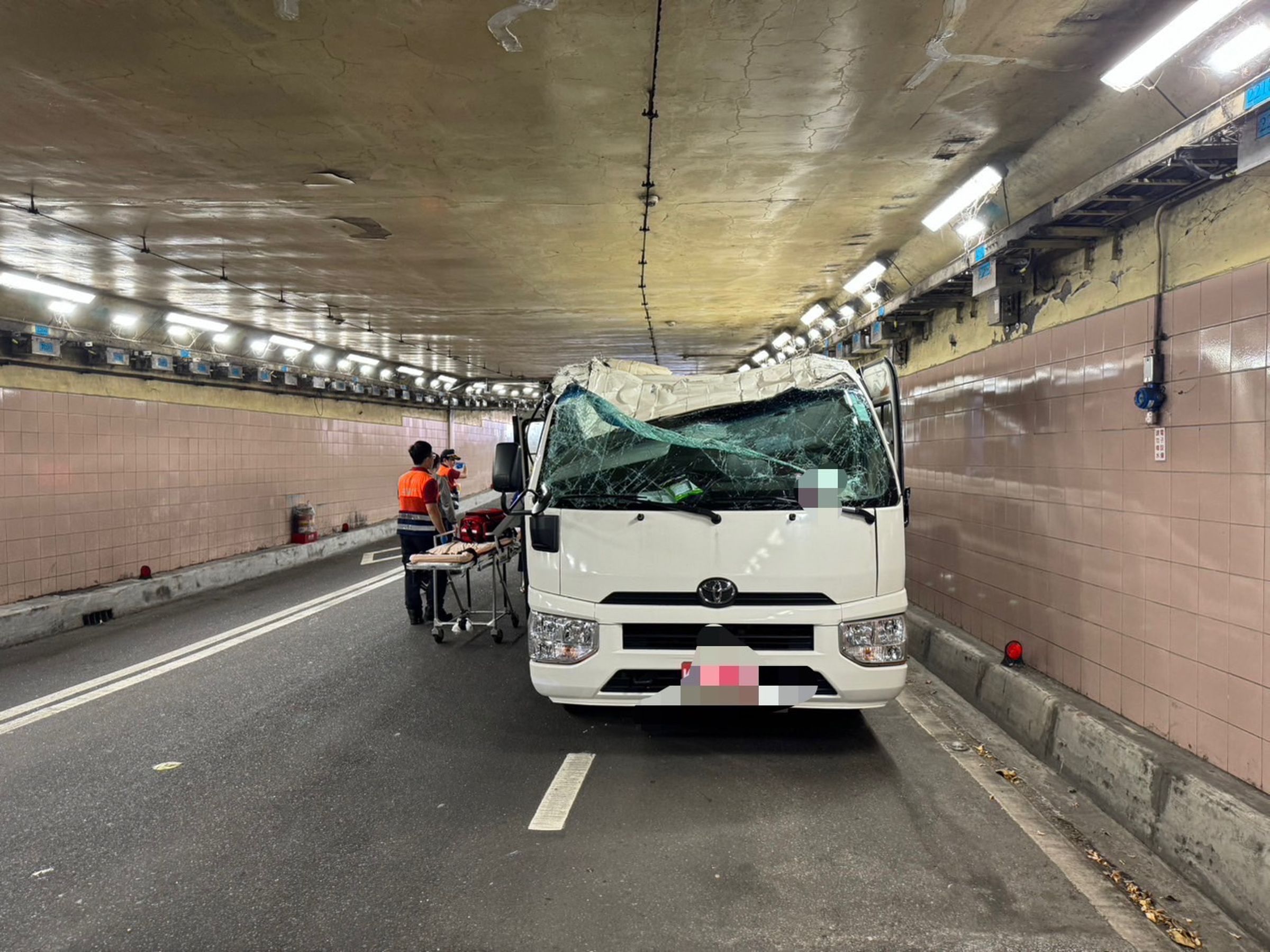 張男駕駛小巴未注意限高硬闖基隆路地下道,導致車頂嚴重凹陷卡在路上。(翻攝畫面)