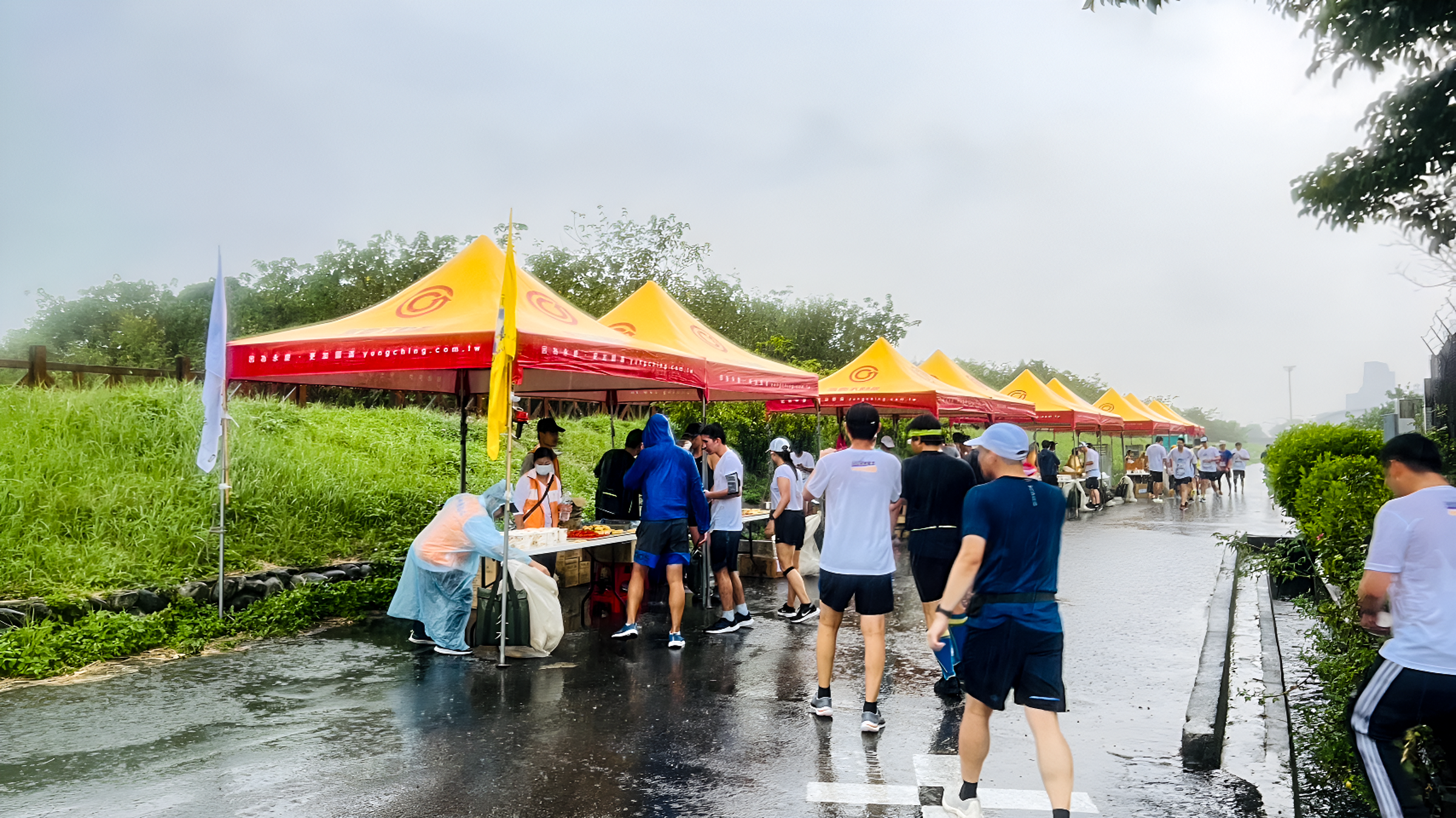 新竹馬拉松陰雨綿綿,永慶加盟四品牌提供的160頂帳篷發揮效果,讓民眾有地方躲雨休憩。(永慶房產集團提供)