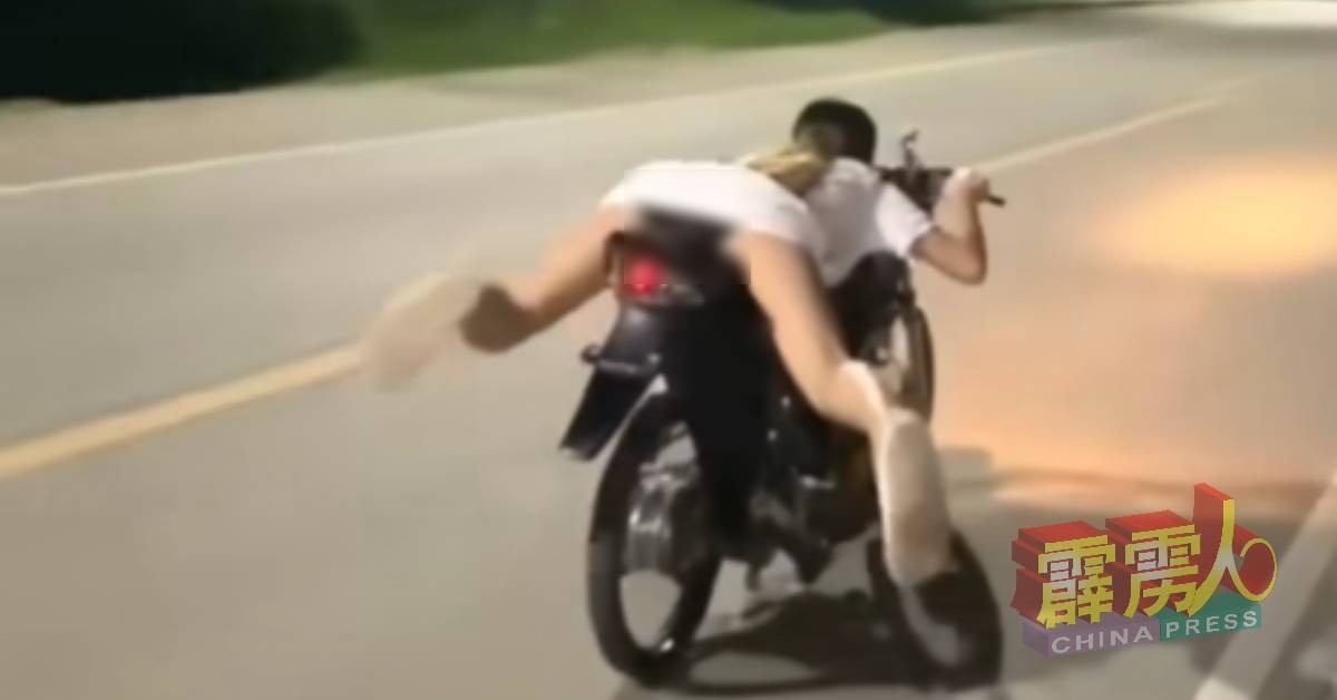 女子因為身穿白色連身短裙，加上趴在摩托車上的姿勢，導致她當場洩春光。（翻自《中國報》）