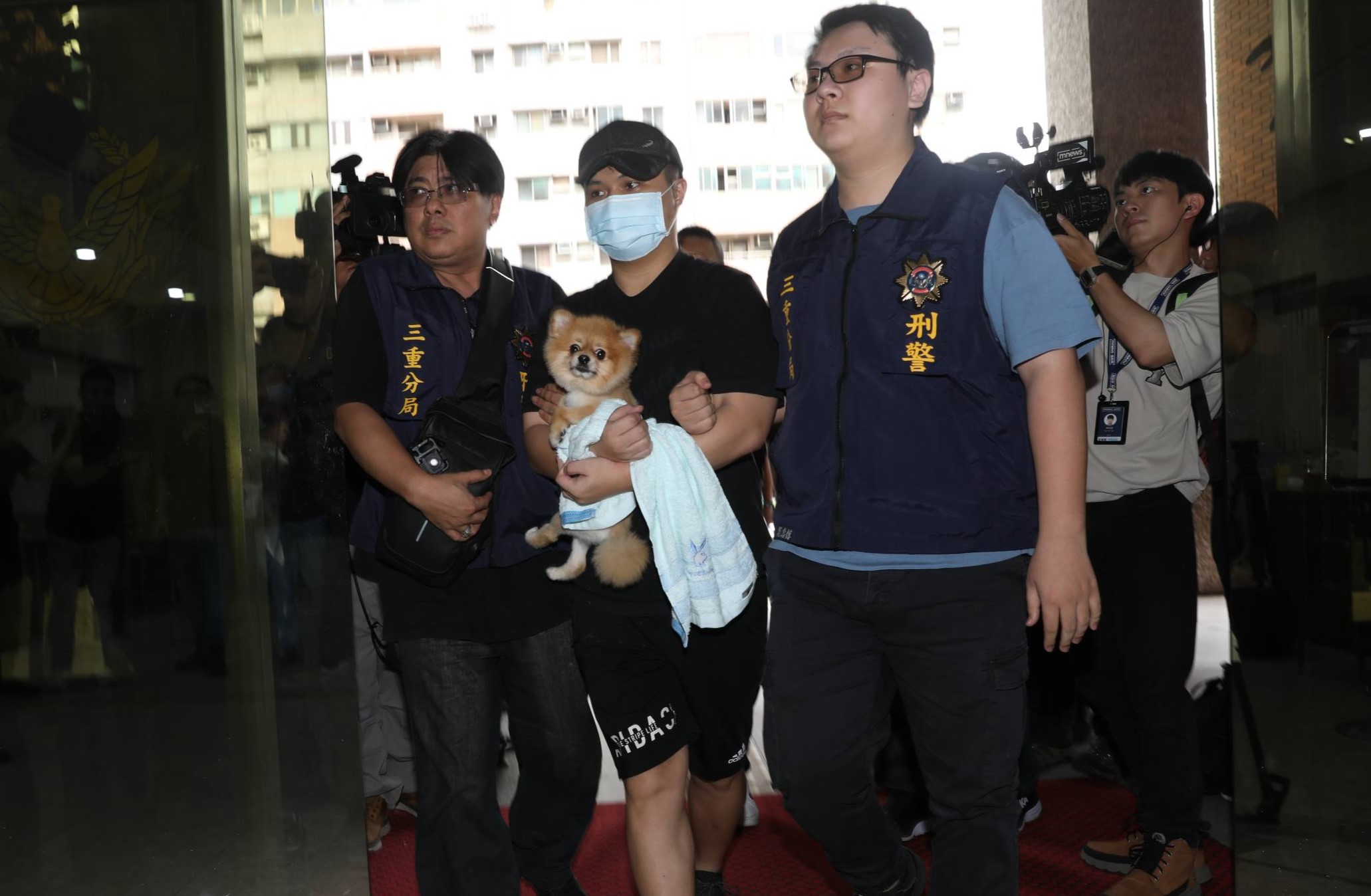 張姓凶嫌被逮捕進警局時，胸前還緊緊抱著寵物狗，讓網友笑酸「乾脆說狗才是主謀」。