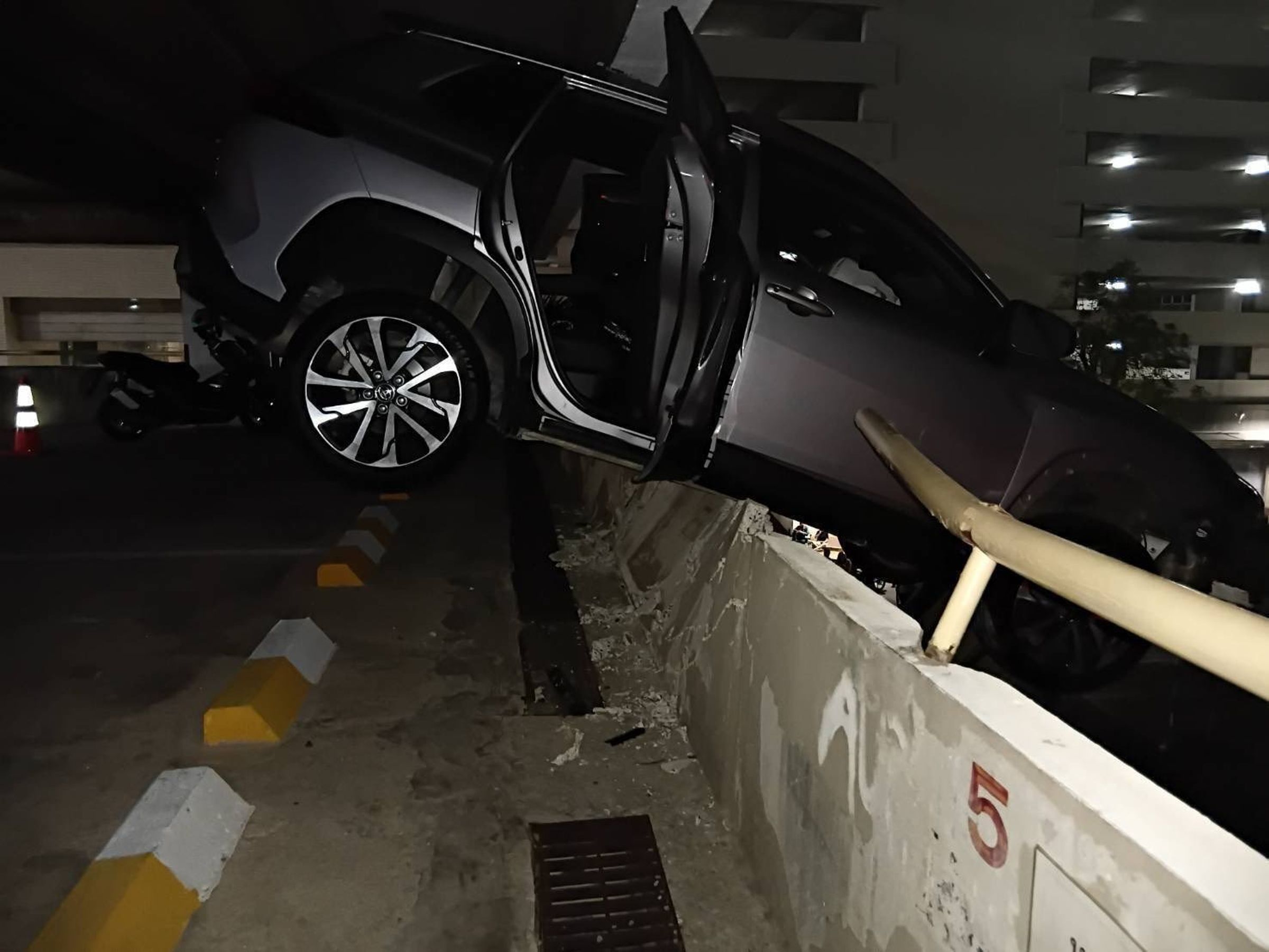 1輛休旅車失控衝破外牆,車頭懸空掛在樓層邊緣,整輛車搖搖欲墜。(翻攝自Sittipon Benz FB)