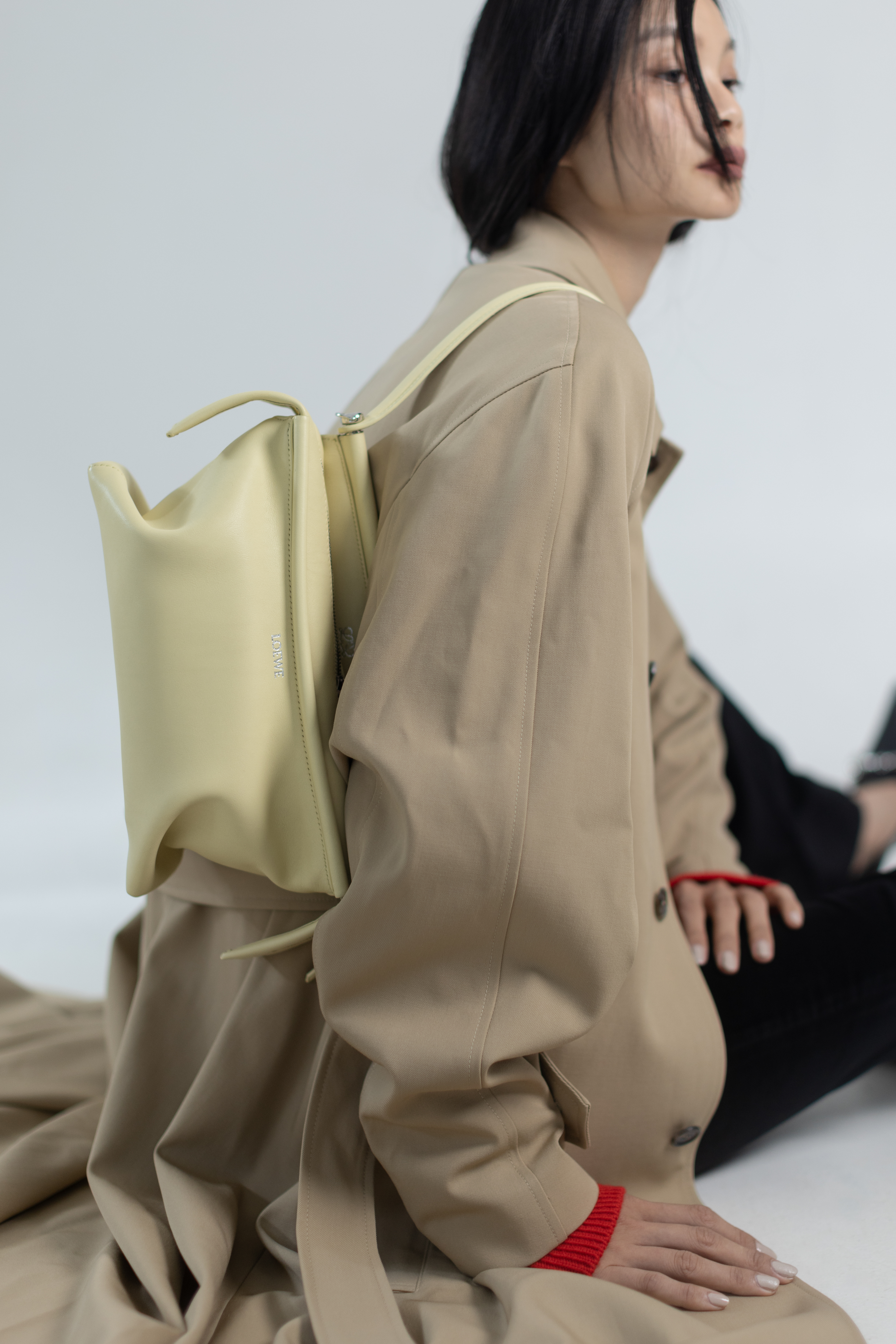Whisker香草色亮面小牛皮包款 NT$112,000 by LOEWE；風衣 價格店洽 by CELINE；圓領毛衣 NT$69,000 by CELINE；喇叭型牛仔褲 價格店洽 by CELINE；高跟鞋 價格店洽 by GUCCI。