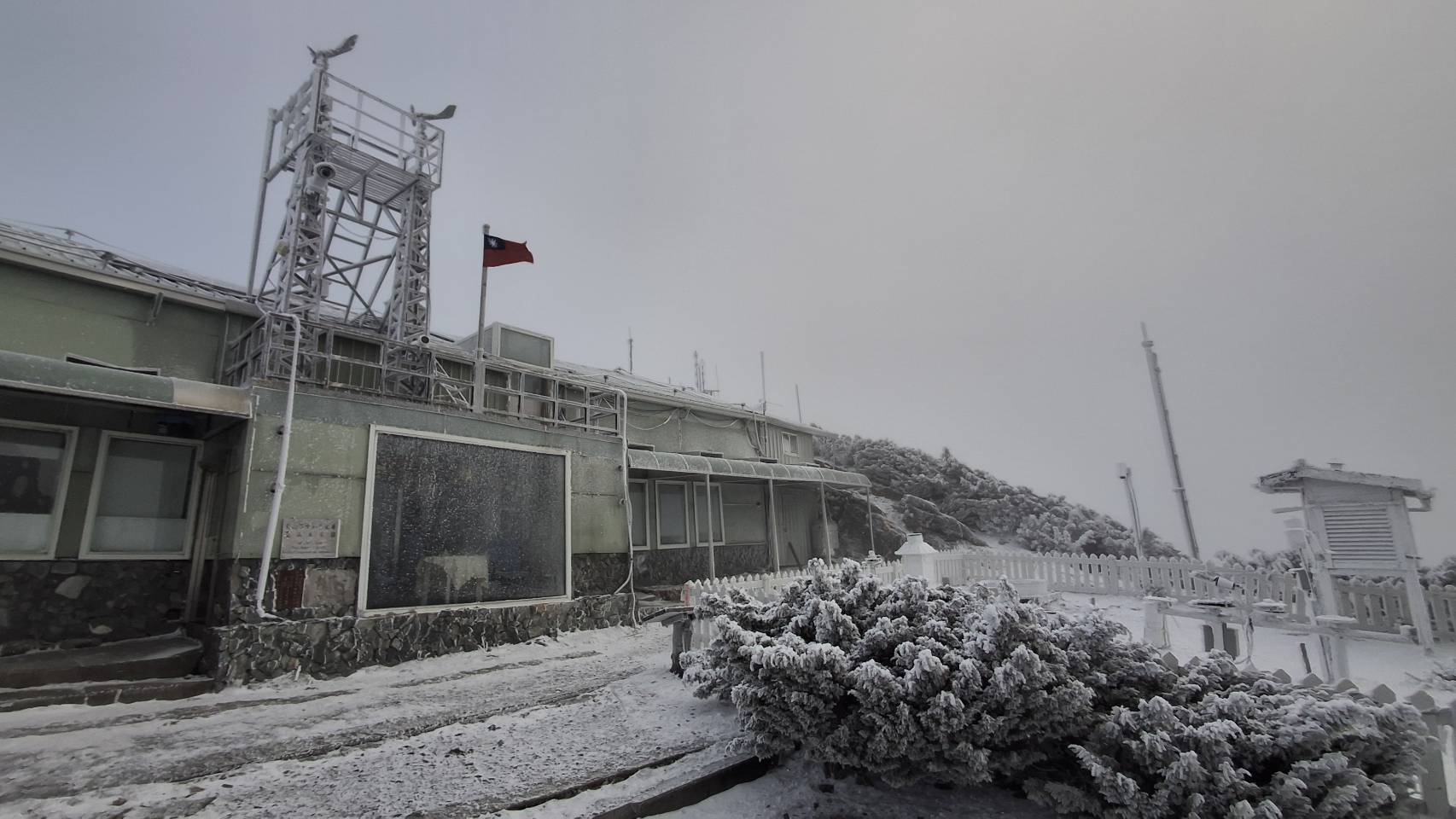 玉山氣象站今6時許觀測到降雪,8時仍在降雪中,可以看到氣象站壟罩在一片雪白中。(翻攝自臉書@報天氣 - 中央氣象署)