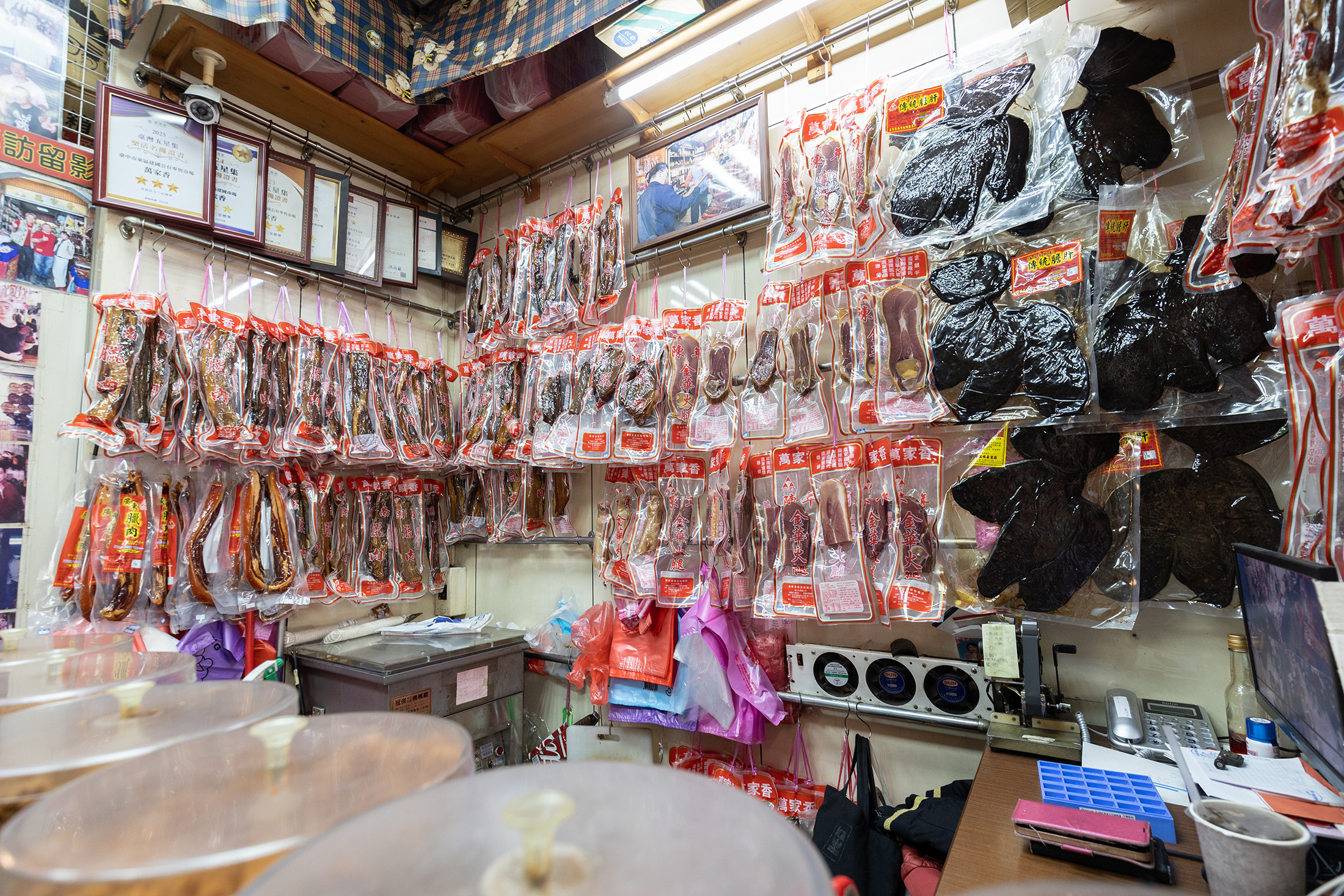 走進萬家香，抬頭便是玲瑯滿目的臘味牆，臘肉、火腿與膽肝交織懸掛，展現店家深厚的製作工藝。