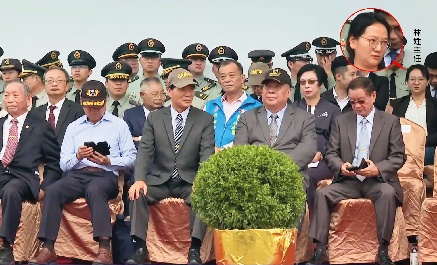 林姓主任陪江啟臣出席M1A2T成軍典禮,並坐在觀禮台上,引發側目。(翻攝M1A2T戰車成軍典禮直播)