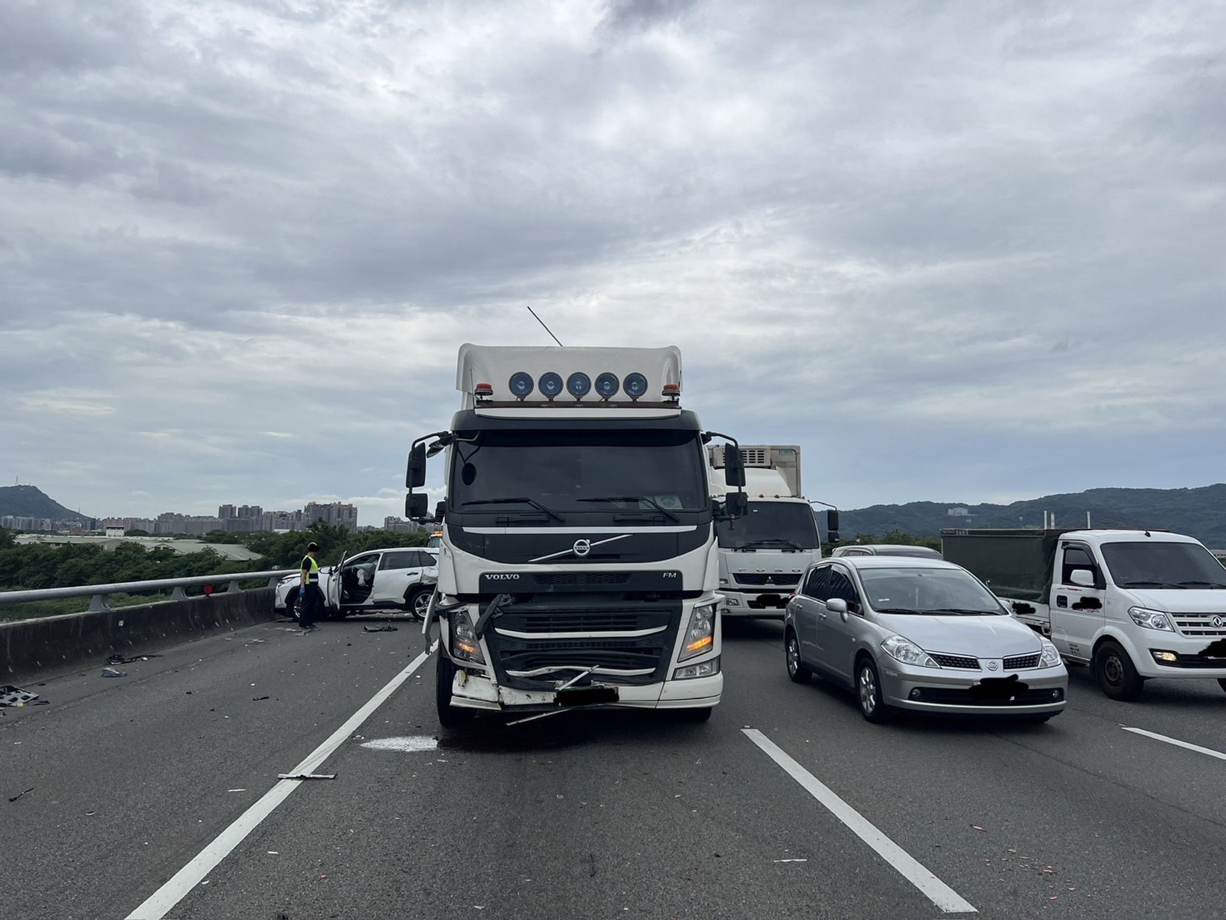 肇事聯結車車頭毀損，一輛遭撞的白色轎車打橫在外側車道。（翻攝畫面）
