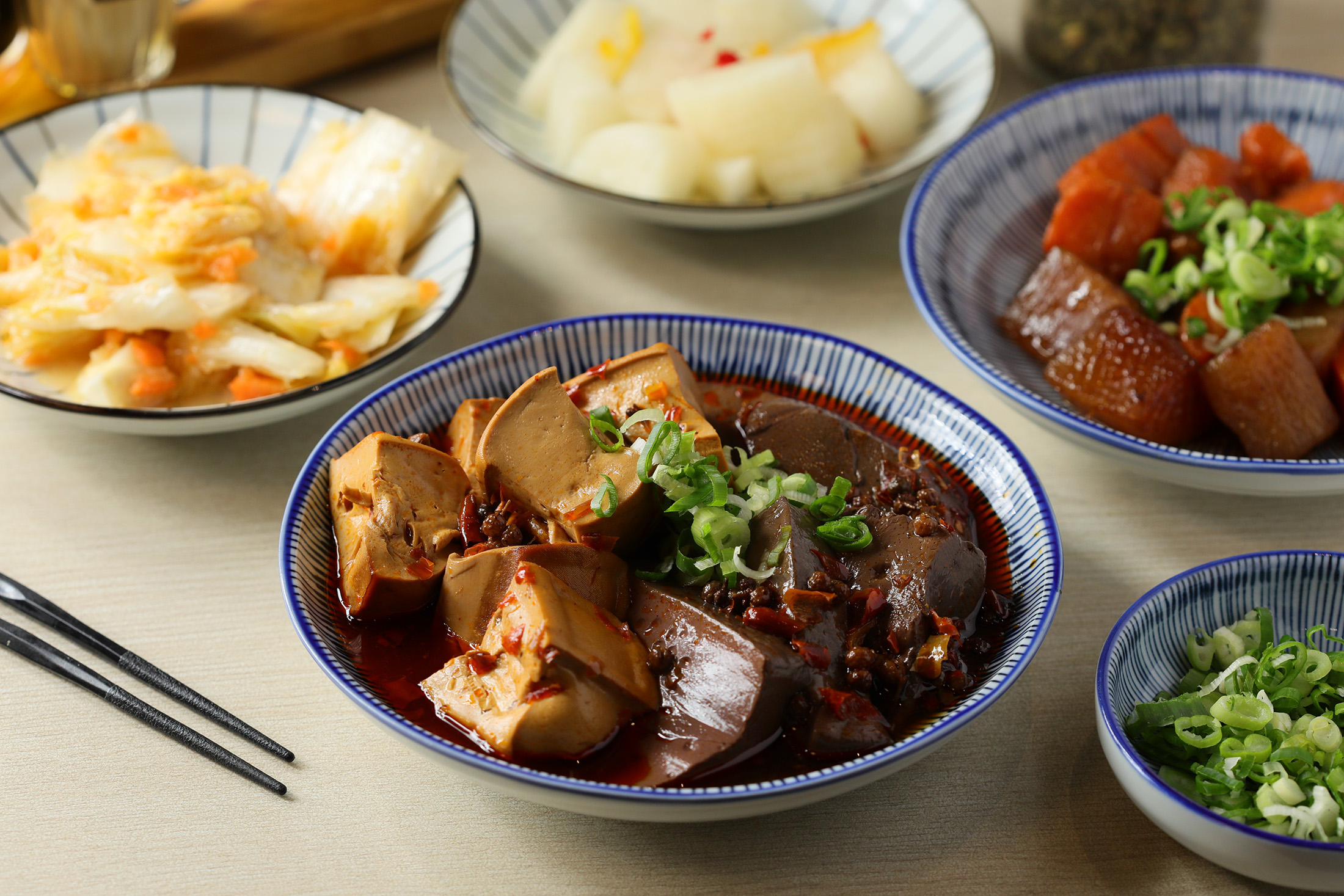 竣師父的小菜選擇多樣, 有「麻辣鴨血豆腐」(前,80元/份),也有「滷紅白蘿蔔」(右起逆時針)和「柚香蘿蔔」「黃金泡菜」(皆40元/份)等清爽泡菜。
