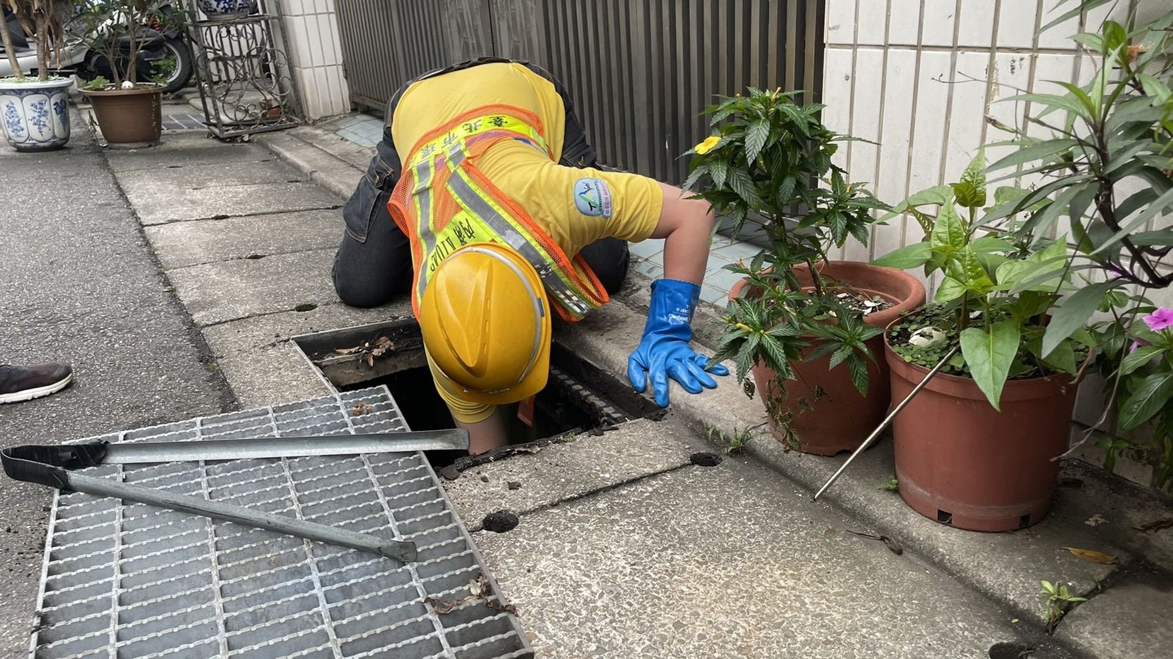 環保清潔隊員為民眾撿拾掉落側溝的物件。(北市環保局提供)