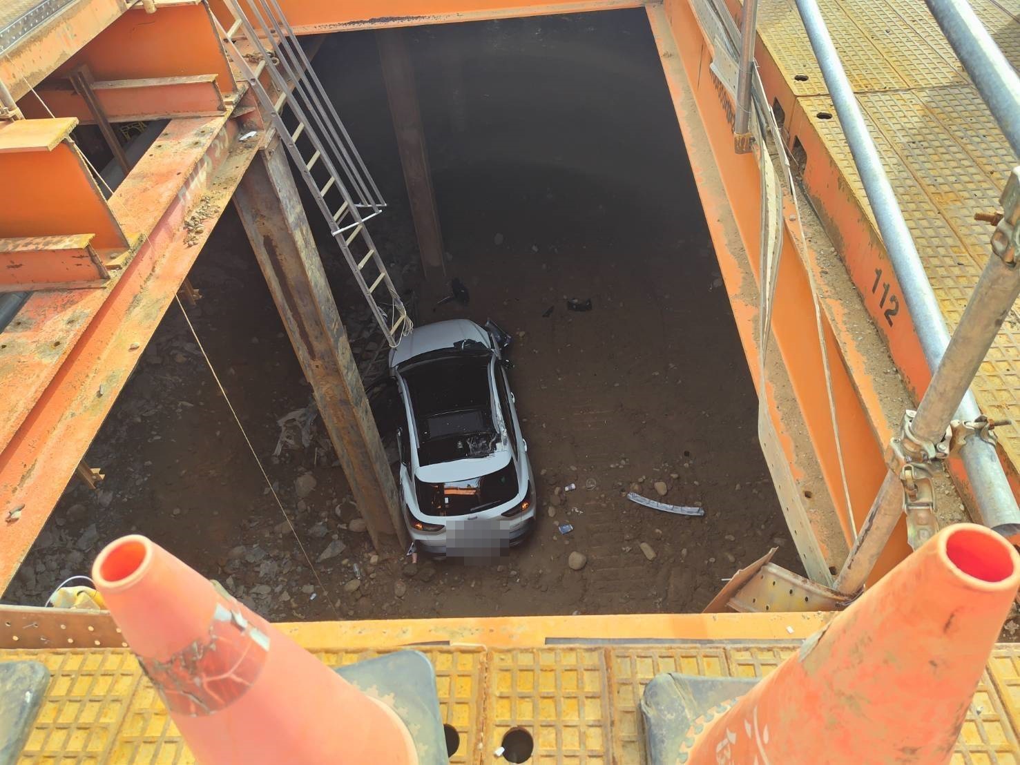 桃園女駕駛今日下午疑似恍神，竟駕車直闖捷運工地，掉進正在開挖的地下室。（翻攝畫面）