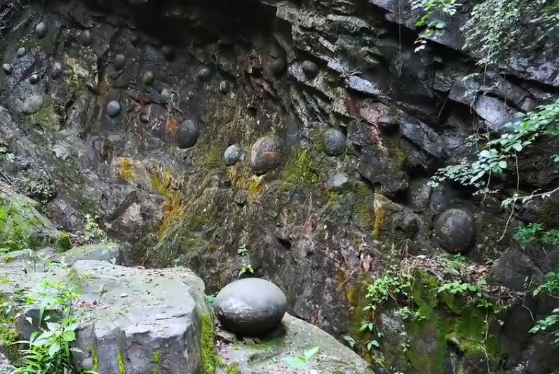 貴州山區有面石壁每隔30年會脫落圓形石蛋，令人嘖嘖稱奇。（翻攝YT頻道「鄉村阿泰」）