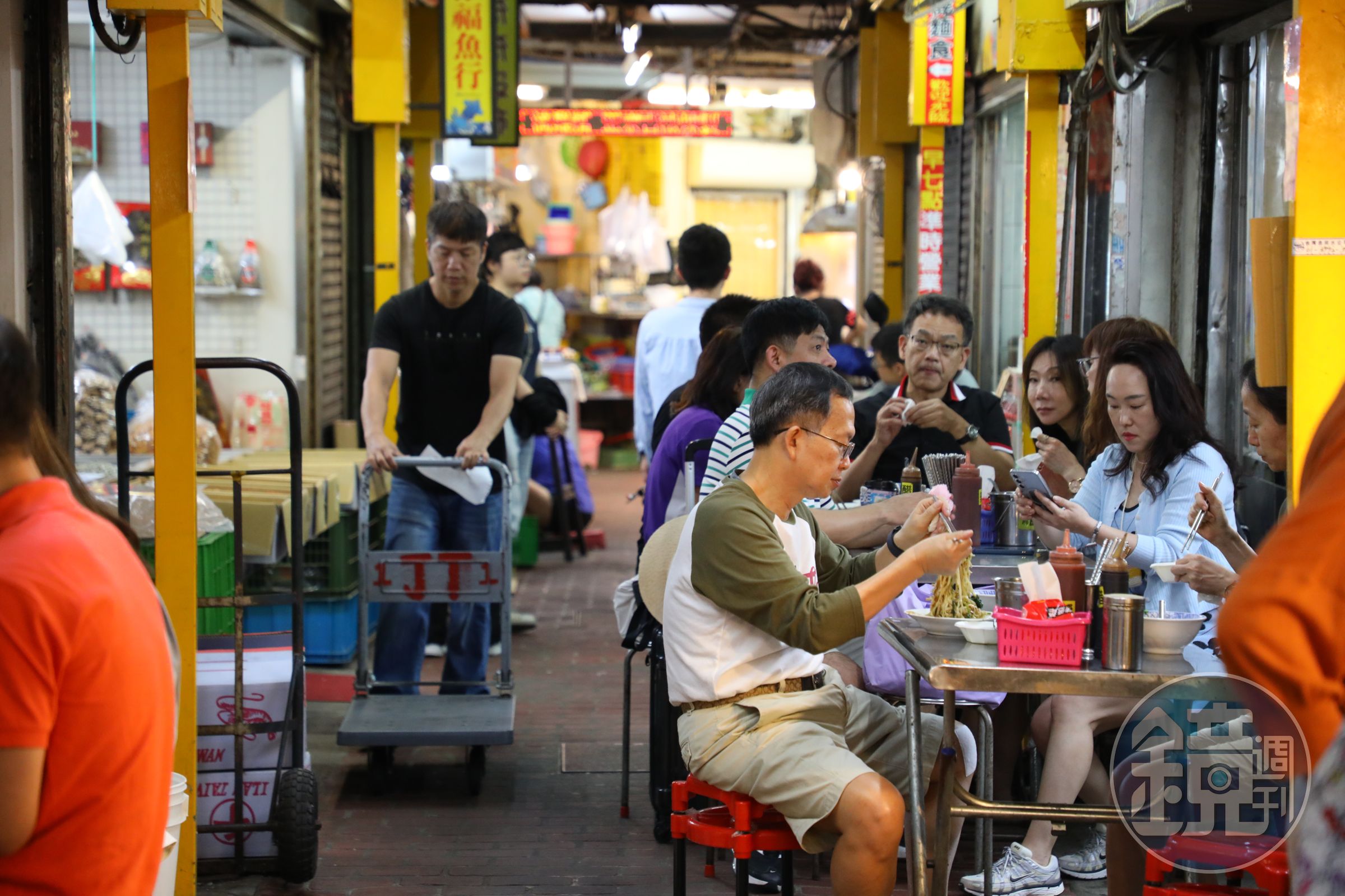 食客們坐在擺在走道上的簡陋桌椅，開心地大快朵頤。
