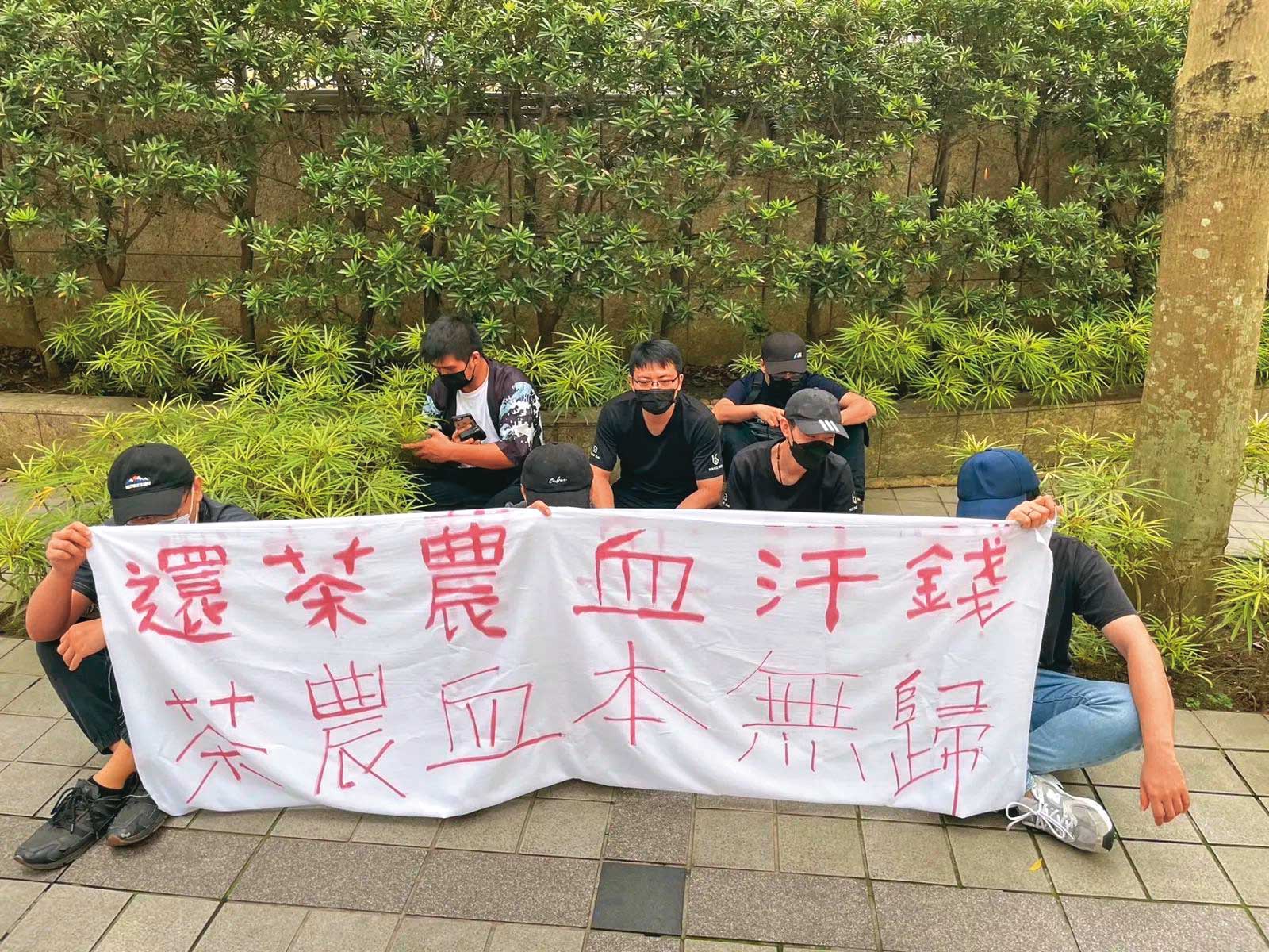 今年4月有一群自稱茶農的黑衣人，前往郭台銘位於北市信義區的豪宅門口，拉白布條抗議。（讀者提供）