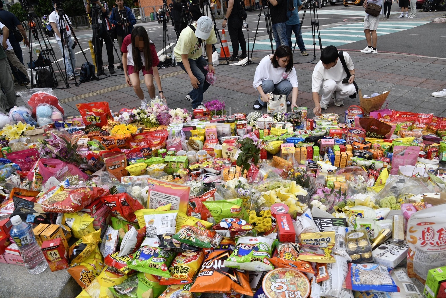 新北三峽北大國小外的公園草坪已堆滿花束、蠟燭、卡片、零食飲料等追思物。（鏡報新聞網李智為）