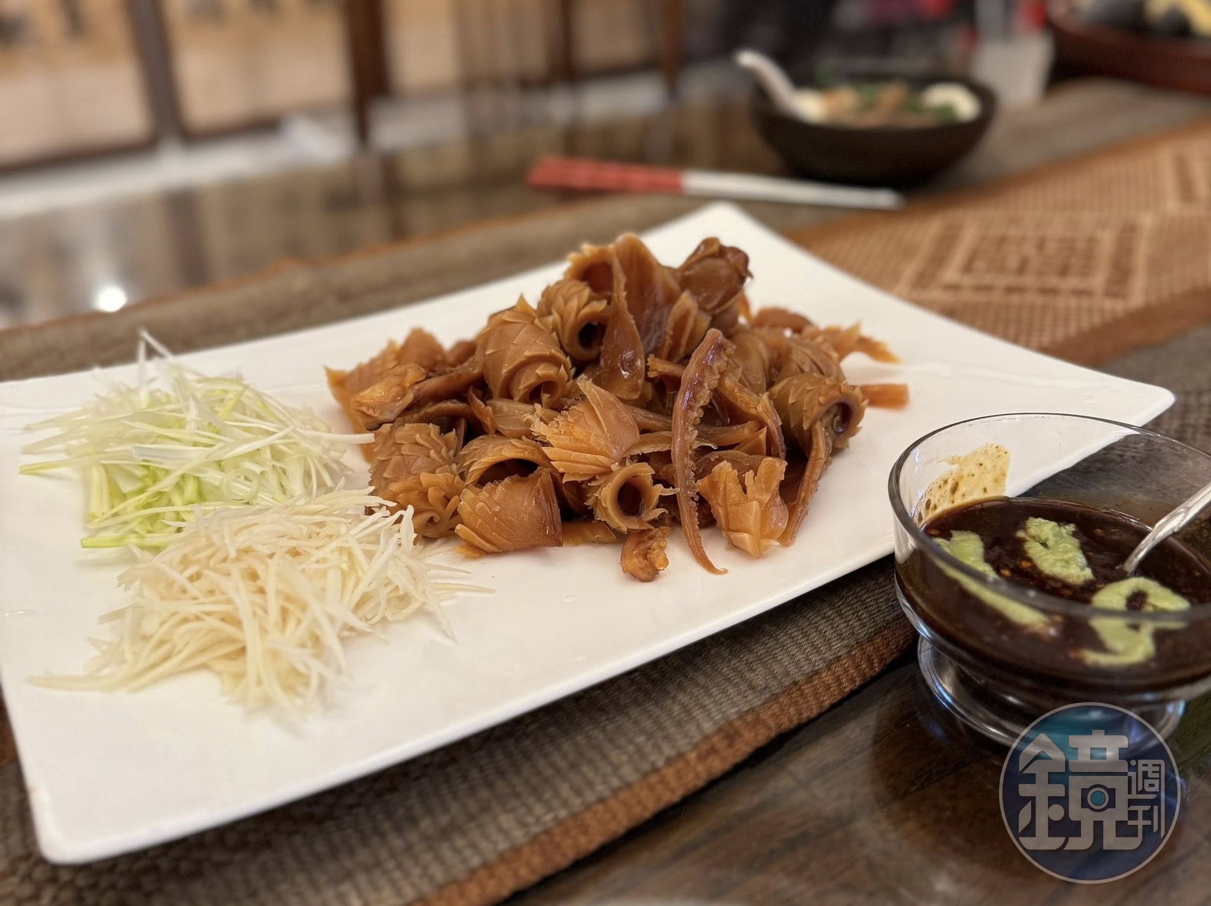 燙魷魚擺上嫩薑絲、蒜苗絲上桌，沾醬是五味油膏加芥末。