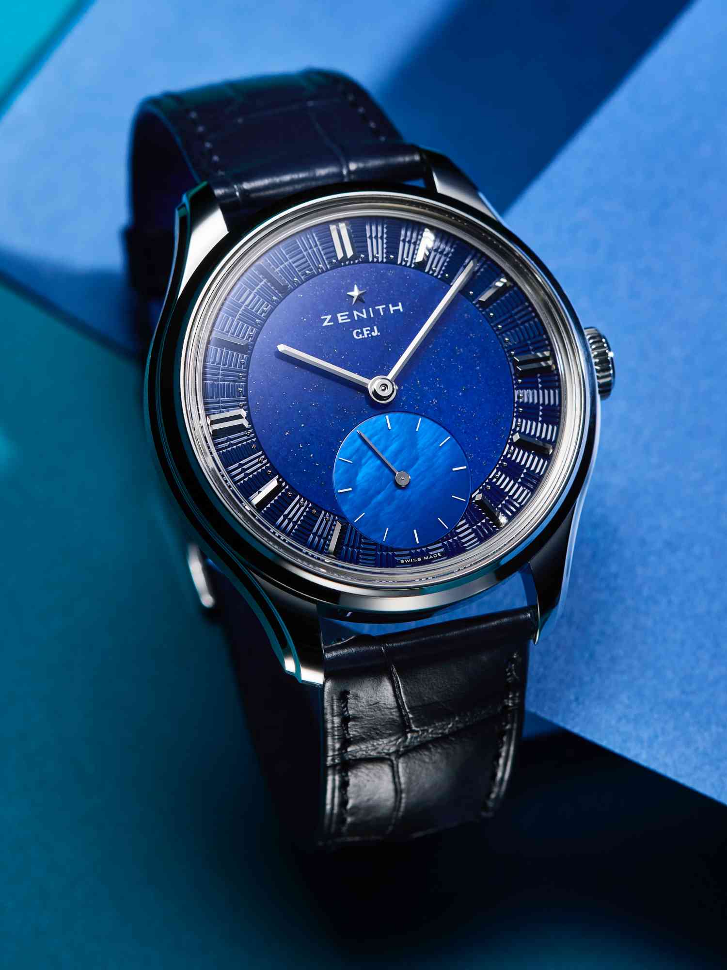ZENITH 向創辦人致敬的全新 G.F.J.腕錶系列，呼應 1950 年代的古典優雅風格，39毫米錶徑搭配10.5毫米的厚度，為目前正裝腕錶最適宜的尺寸。面盤採用複雜的三層式結構，並呈極細微的圓弧。藍色基底的面盤外緣飾以與機芯橋板一致的「磚形」機刻雕花，鑲嵌18K白金立體時標，分鐘刻度則由 40 顆手工鑲嵌的 18K 白金珠粒構成，工藝細膩且耗時。而中央區域選用深藍色青金石，小秒盤則採用藍色珍珠母貝，與纖細的18K白金棒狀指針，構成簡潔優雅的盤面。採用珍貴 950鉑金材質，確立了其頂級定位，未來也會全系列使用貴金屬。 功能：時、分、小秒針指示 機芯：手上鏈機芯 定價：約NT$1,779,800（限量160只）