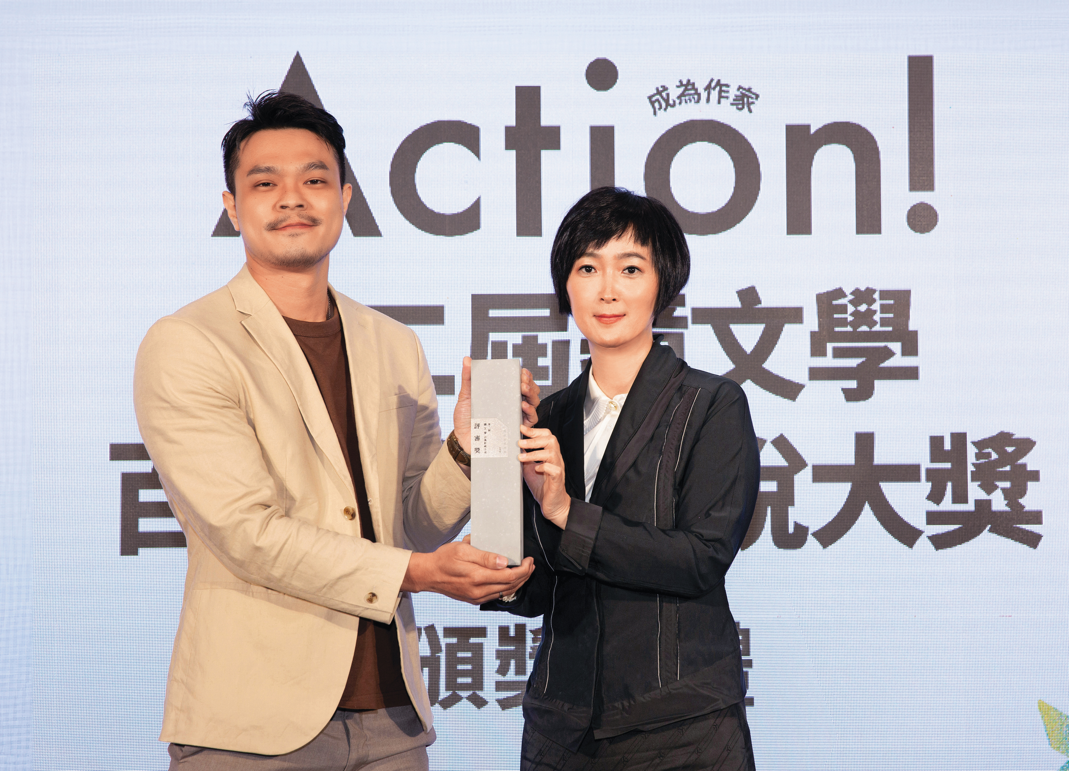 吳威邑（左）以《最後的魔術家族》獲第2屆鏡文學百萬影視小說大獎評審獎，由鏡文學總經理兼總編輯董成瑜（右）頒獎。（鏡文學提供）