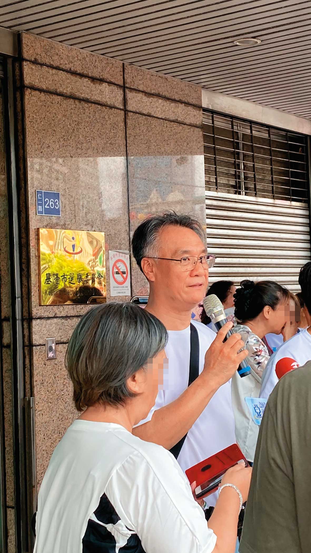 任職於基隆二信的蘇姓公關主任，被拍到手持麥克風，在謝國樑登記現場指揮調度人員。（讀者提供）