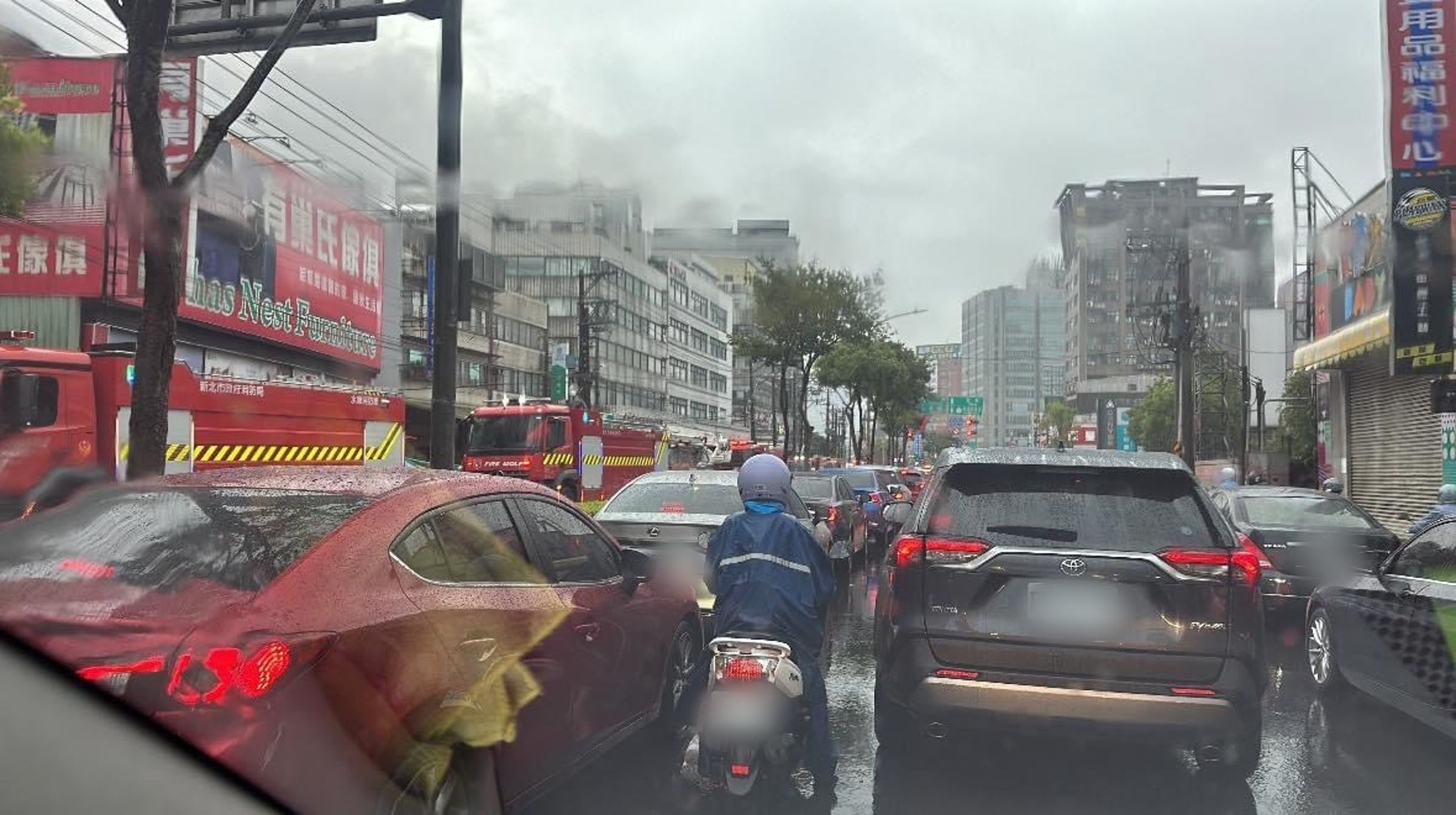 汐止好市多附近民宅火災,導致尖峰時段交通更加壅塞,遠處天空可見濃煙。(翻攝臉書社團「汐止集團」)