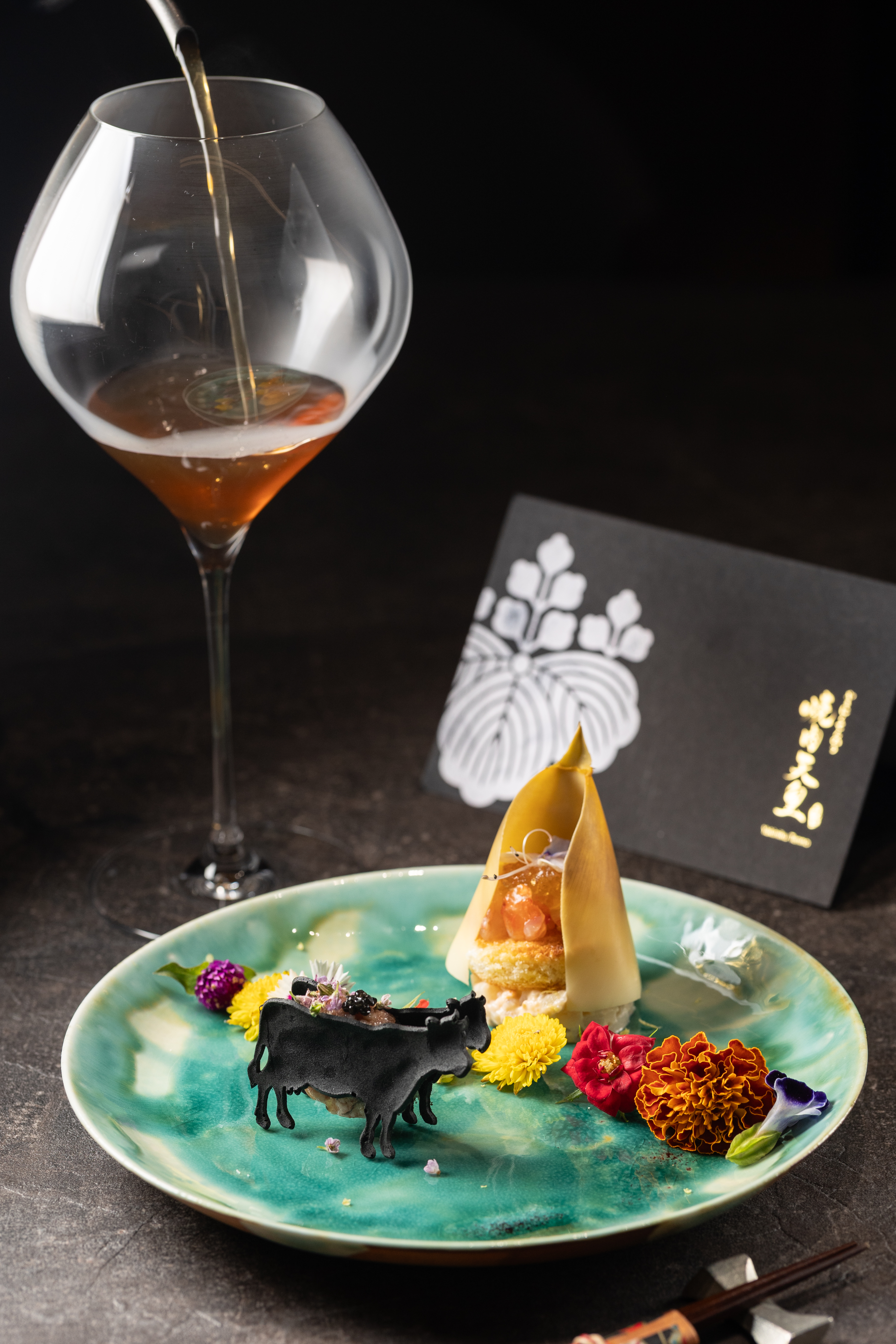 開胃菜「先付」以筍殼包裹鮮筍沙拉，搭配點綴醋凍的生食級靜岡甜蝦；前方和牛造型的竹炭餅乾夾著以和牛尖三角肉製成的生牛肉球和魚子醬。