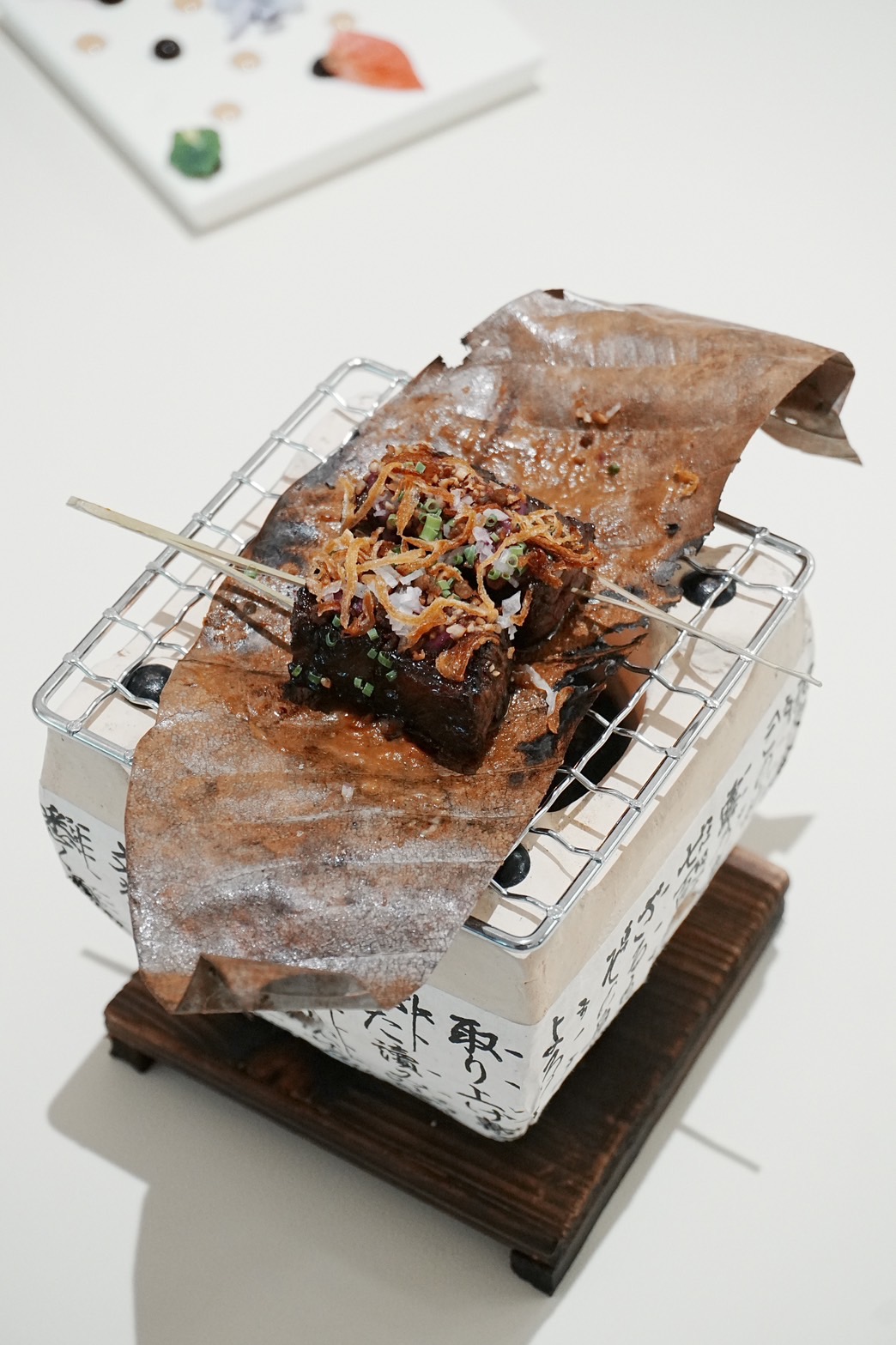 「味噌⽜肋朴葉燒」以煙燻燒烤的朴葉燒呈現秋季炊煙意象，軟嫩鹹香牛小排搭配⿊蒜頭、無花果及楓糖打底的微甜醬汁，鹹甜和諧之餘也保有著肉的旨味。