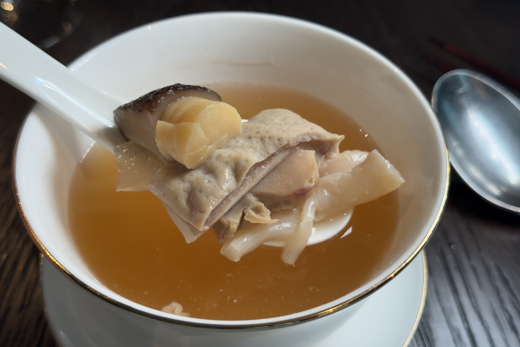 「元貝四寶湯」看似澄澈的湯頭，背後是兩日工序，以老母雞、雞腳、火腿與赤肉熬製，集干貝、螺頭等鮮味於一碗。