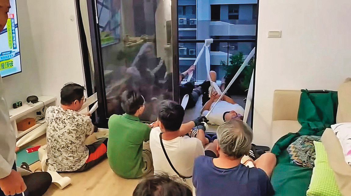 新竹某高樓住戶合力用消防水帶固定搖搖欲墜的玻璃陽台。（翻攝爆料公社）