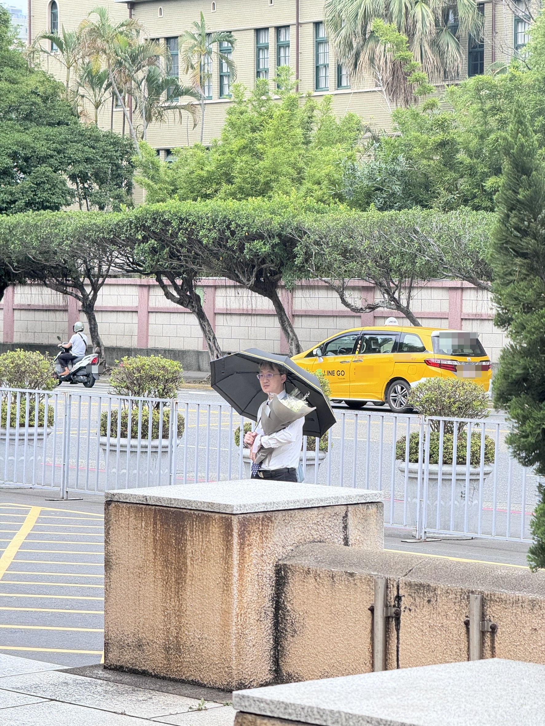 基隆地院法官李岳今現身司法院正門口,手捧白花、撐著黑傘,預計他將會在這站上一天。(本刊資料照)