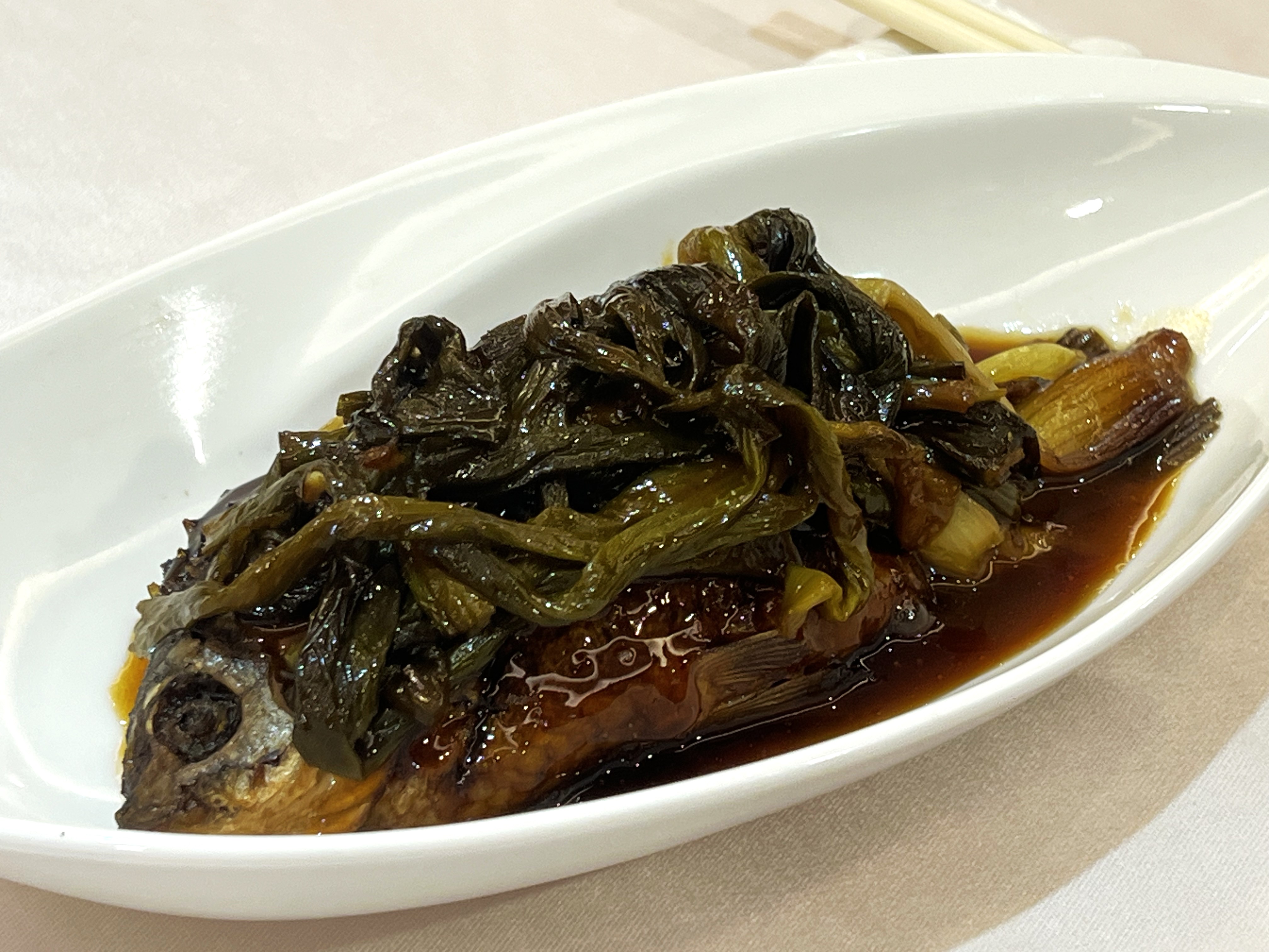 大尾帶卵的「蔥烤鯽魚」非常入味，上頭鋪滿㸆過的青蔥。