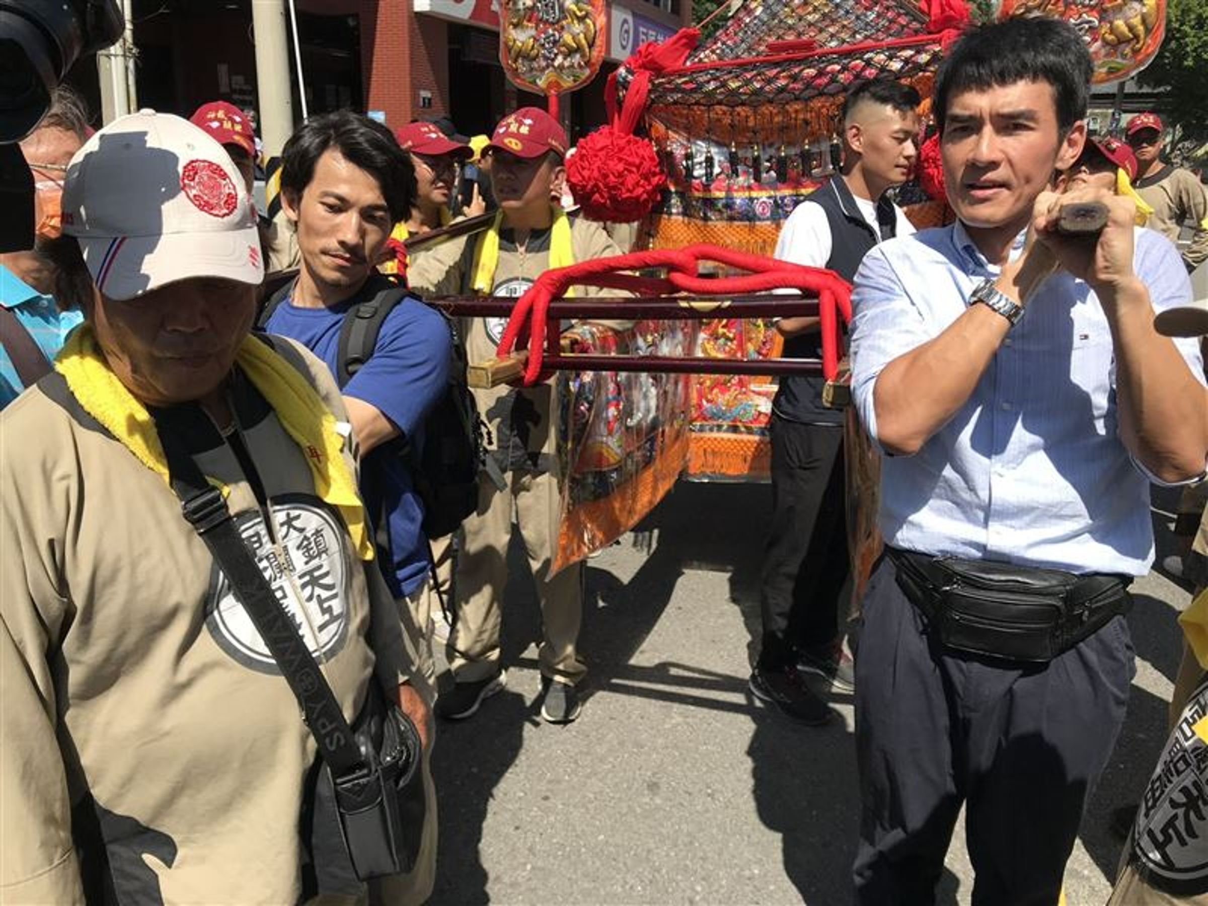 連炳發(左)與楊一展(右)鑽大甲媽祖鑾轎,也與大甲鎮瀾宮大安神轎團一起抬神轎。(「大甲媽祖ㄅㄜˊ 讚」粉絲專頁提供)