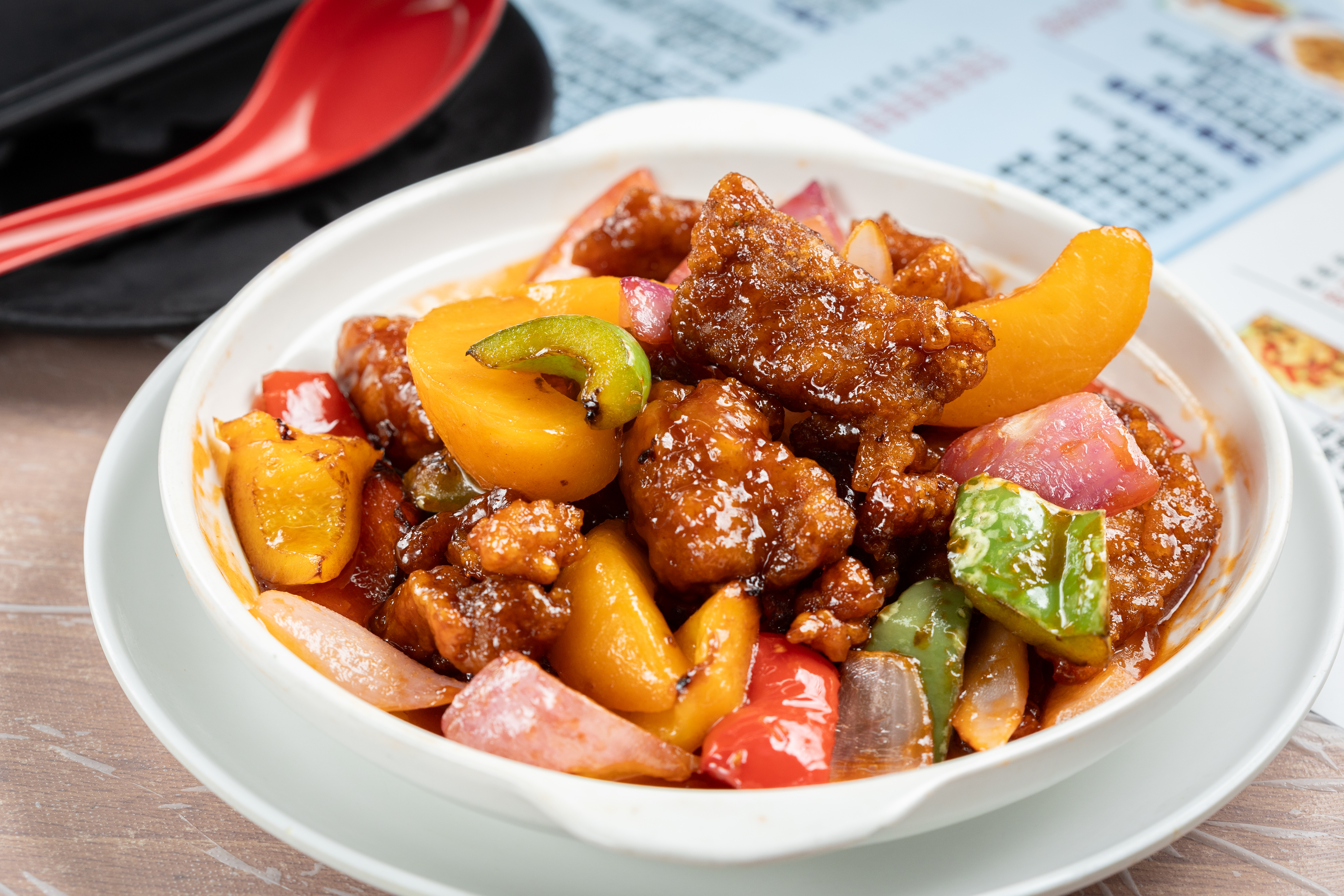 亮記的「蜜桃拔絲真咕咾肉」將炸豬肉塊裹上酸甜醬汁，並改以蜜桃入饌，清新解膩。（港幣88元／份，約NT$332）