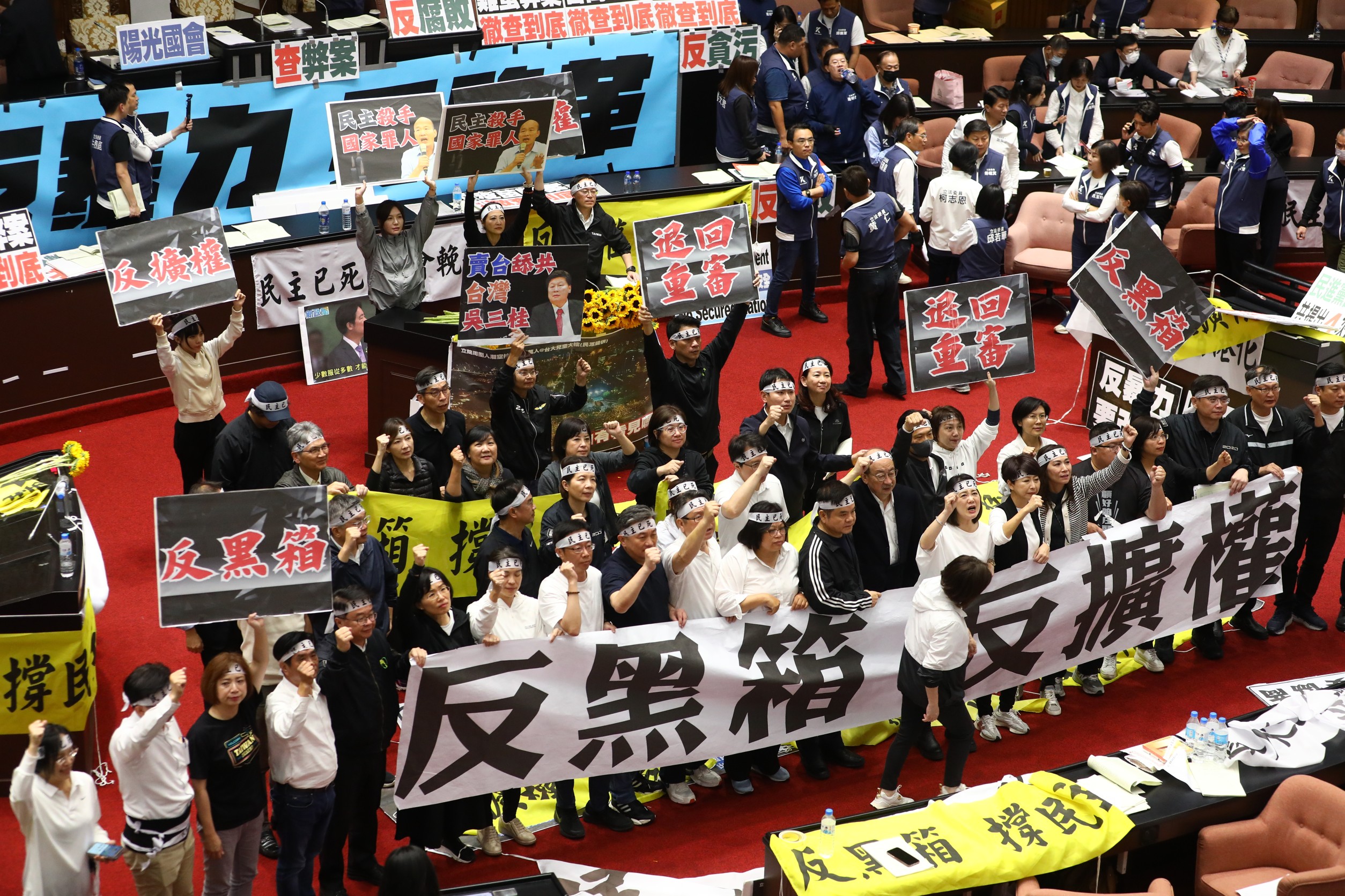 民進黨立委在國會高舉反黑箱、反擴權、退回重審等標語抗議在野黨。