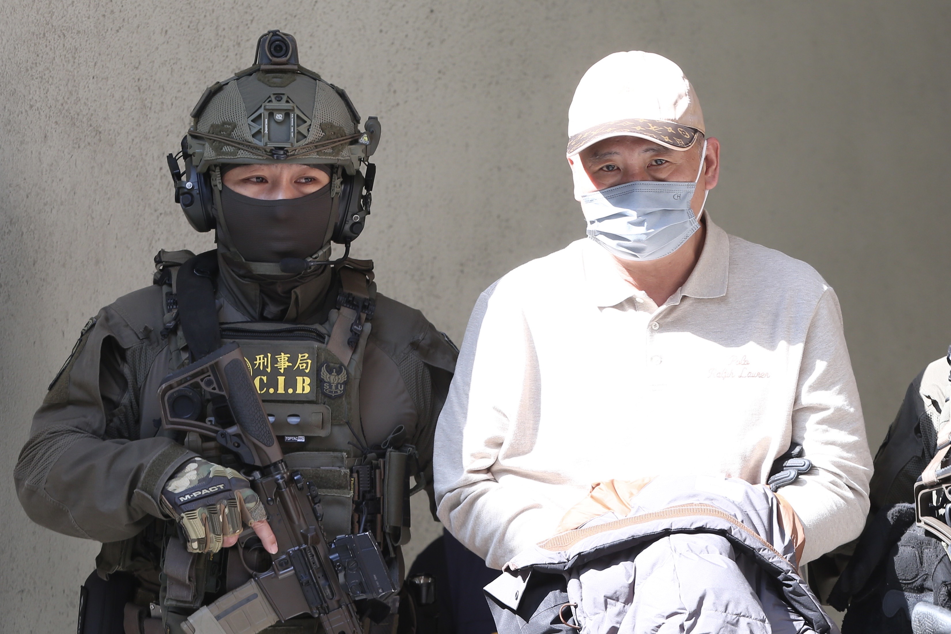 四海幫主張存偉（右）涉犯組織犯罪防制條例、洗錢防制法等案，今天由除暴特勤隊員荷槍實彈戒護從刑事局移送北檢偵訊。（鏡報姜永年）