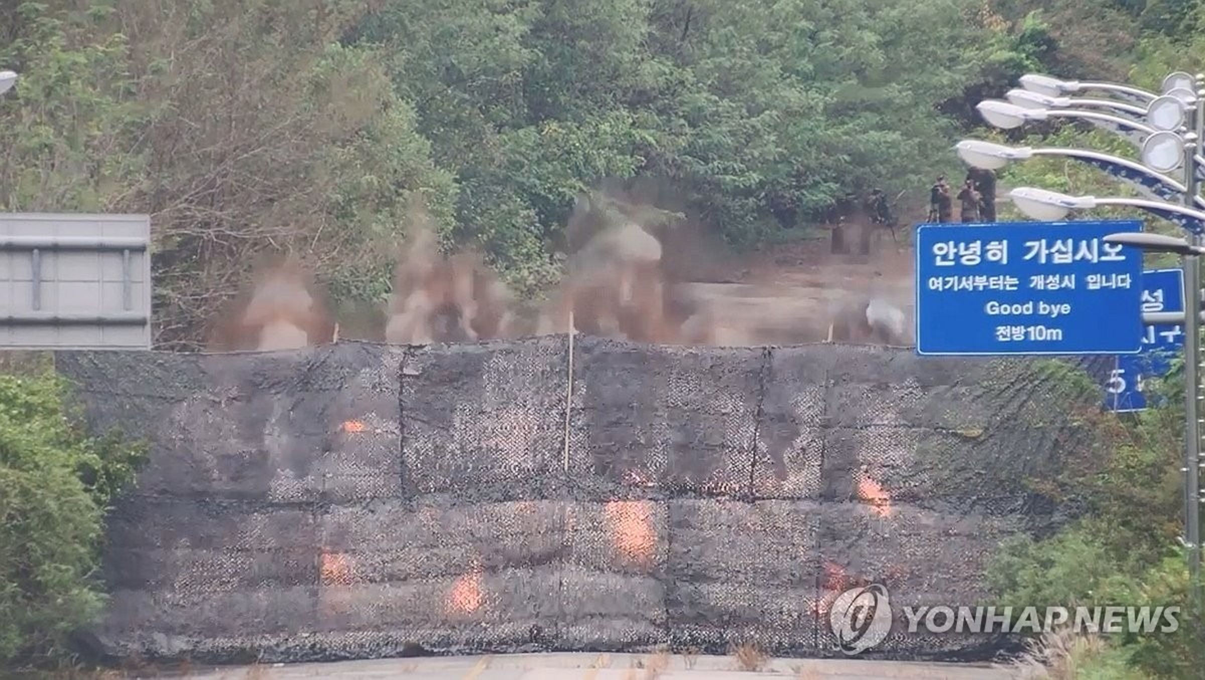 道路藍牌上還寫著「請走好」、「再見」等字樣,後面為北韓軍方進行爆破行動。(翻自《韓聯社》)