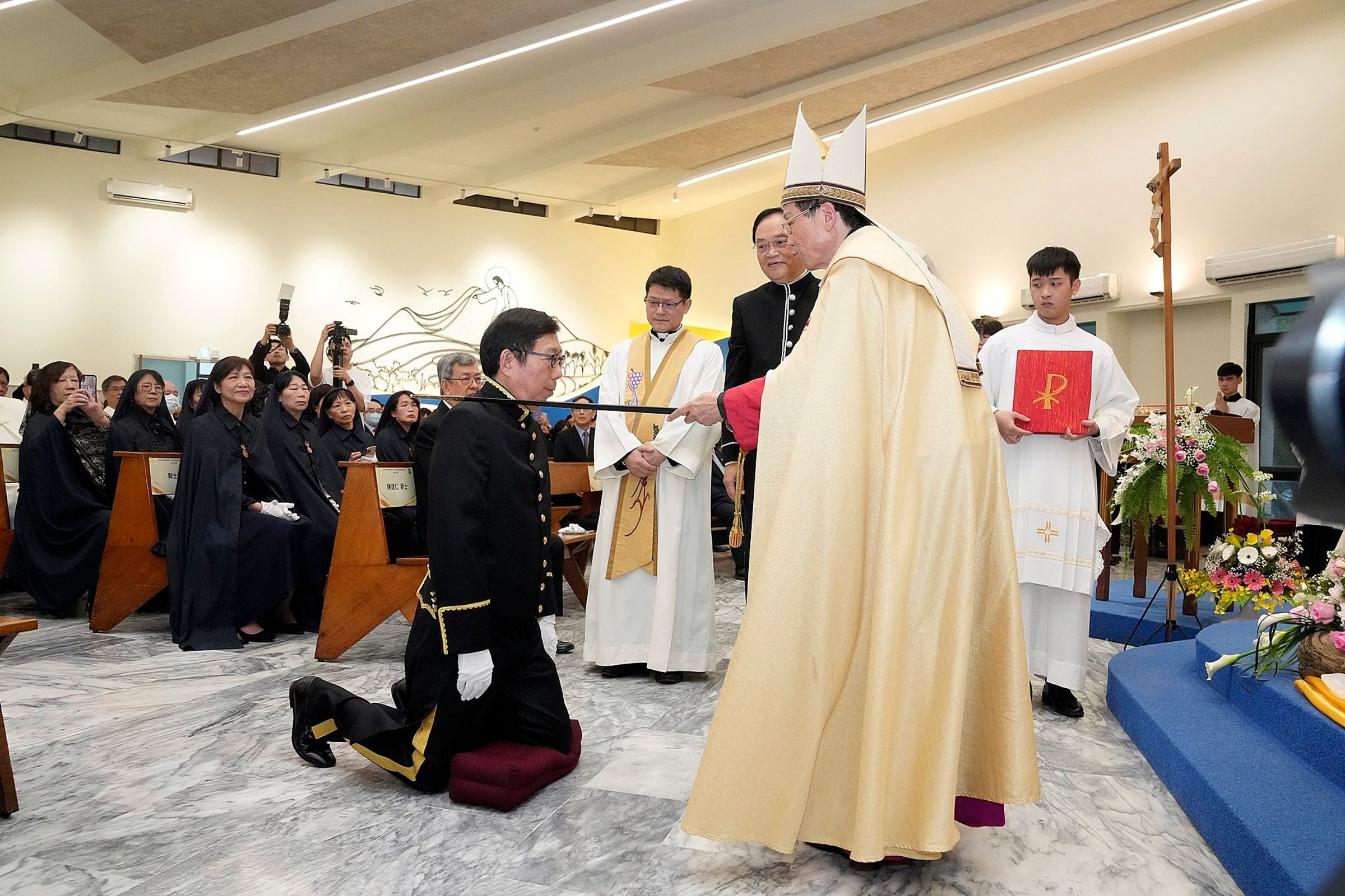 天主教台北總教區總主教鍾安住(右)代表教宗頒授爵位給蔡明興(跪地者)。(翻攝天主教輔仁大學臉書)