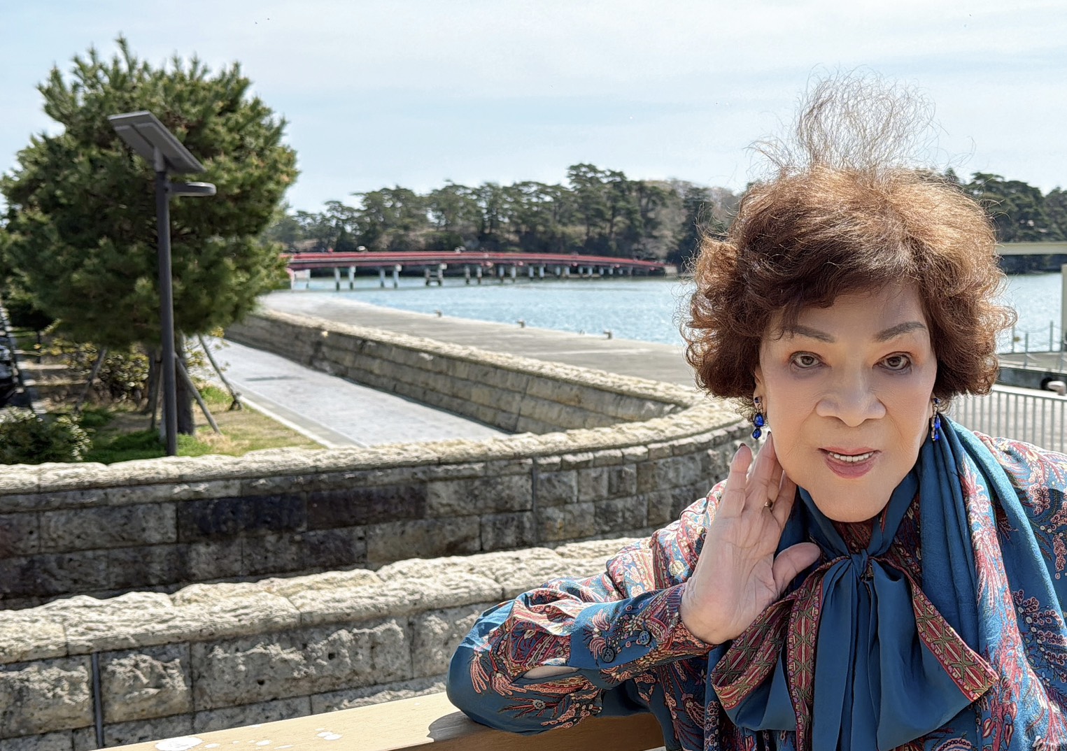 周遊身後紅色的長橋「福浦橋」是台灣人捐贈兩億元興建的。（李朝永提供）