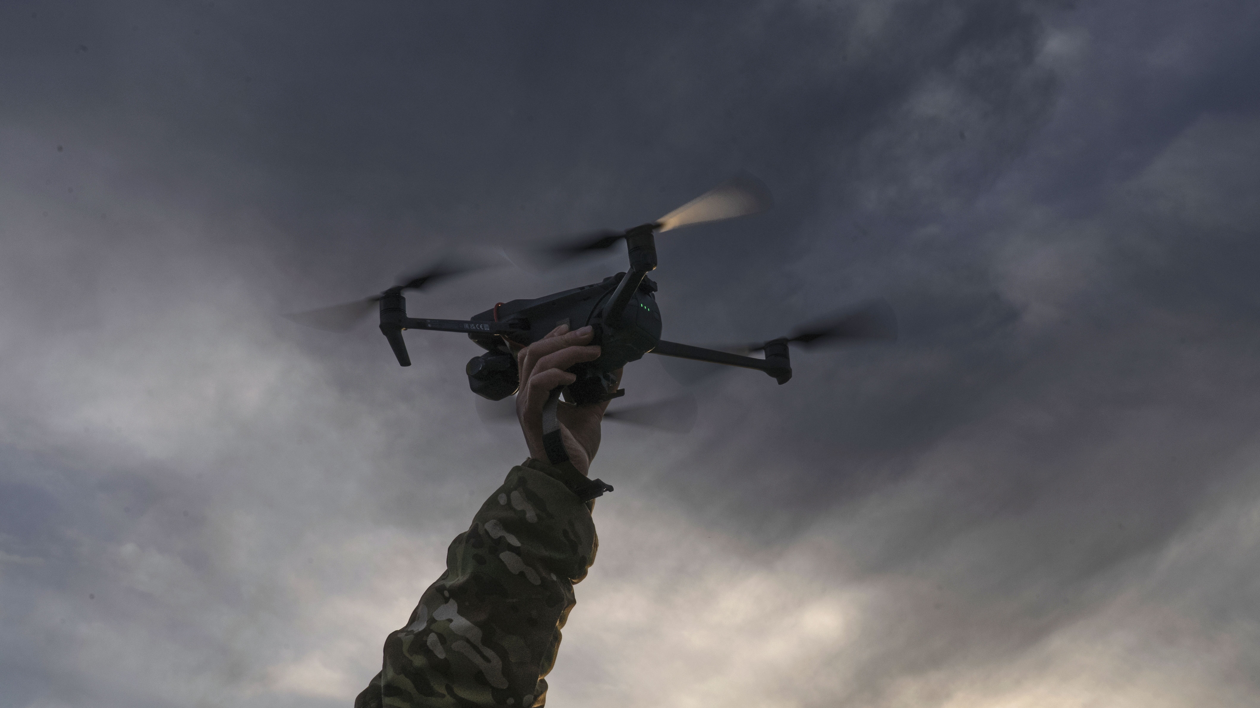 一名烏克蘭士兵伸手接回完成測試任務的無人機。在夕陽下,這趟短暫任務標示了戰場科技進化的又一小步。