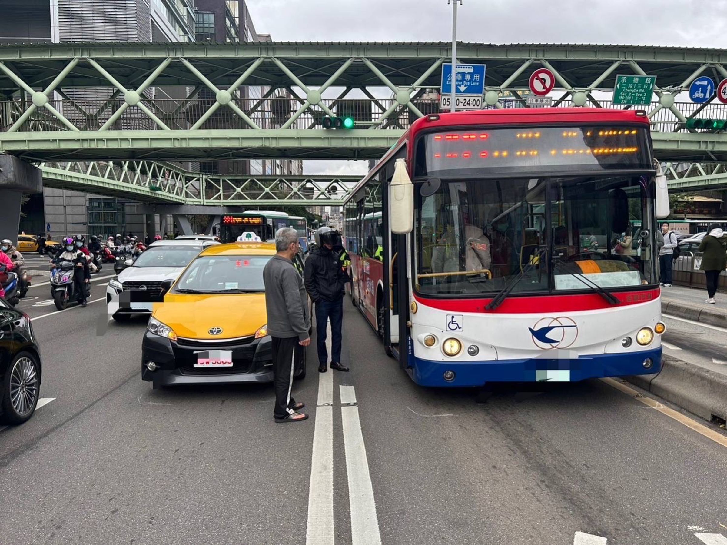 計程車遭後方機車追撞臨停路中，卻因突開啟車門，導致公車緊急煞車7人傷。（翻攝畫面）