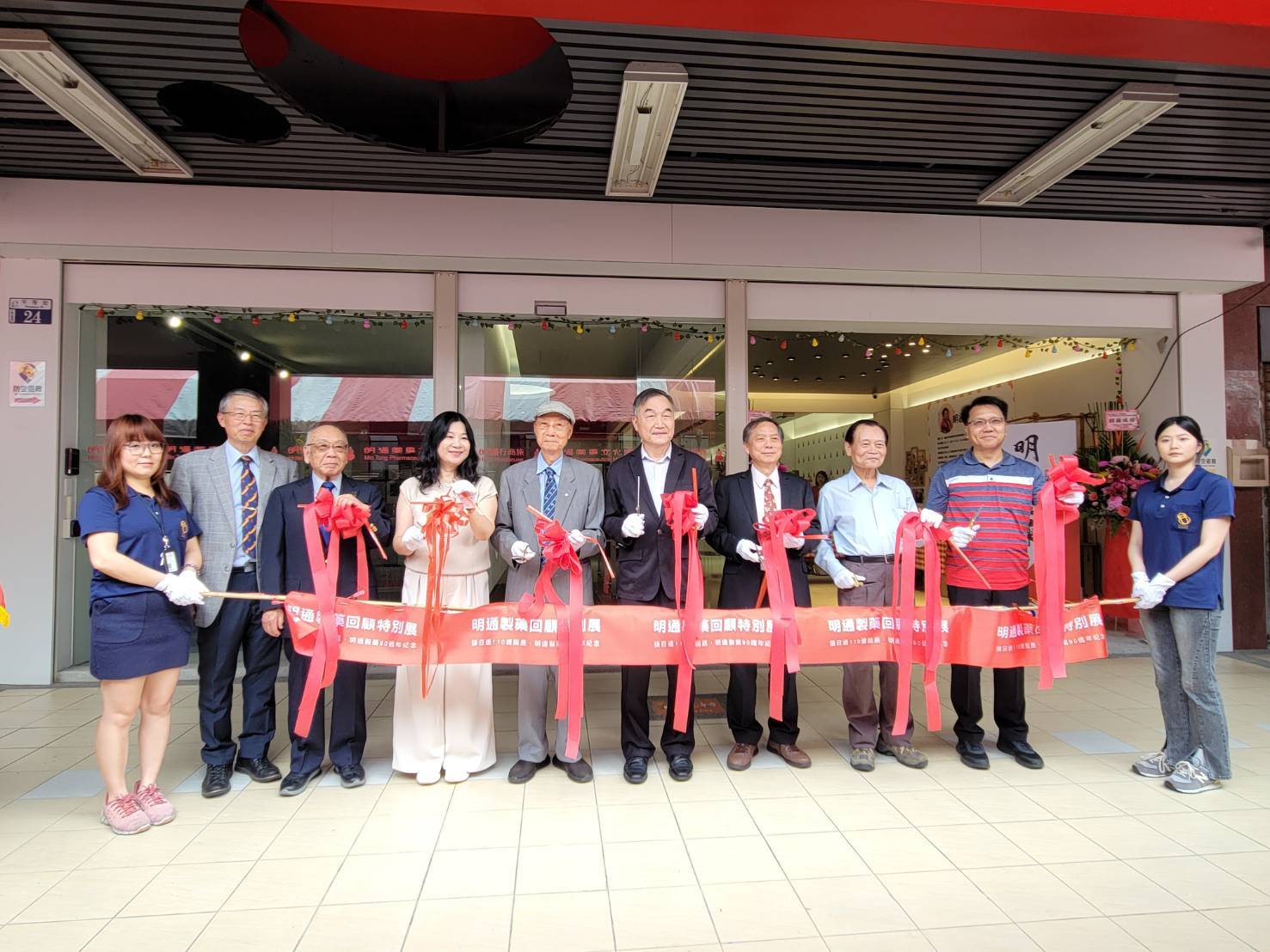 明通製藥90週年慶回顧特展開幕儀式，2025年4月19日於明通行商旅一樓舉行。出席來賓右二起依序為台中市第一警分局長、前法務部長曾勇夫、明通製藥董事長張光明、台中副市長黃國榮、明通製藥第二任董事長張西城、西屯扶輪社樂活健身隊主委徐伴麗、日大齒學部代表野上宏醫師、明通藥事文化館館長張光發。（張光發提供）