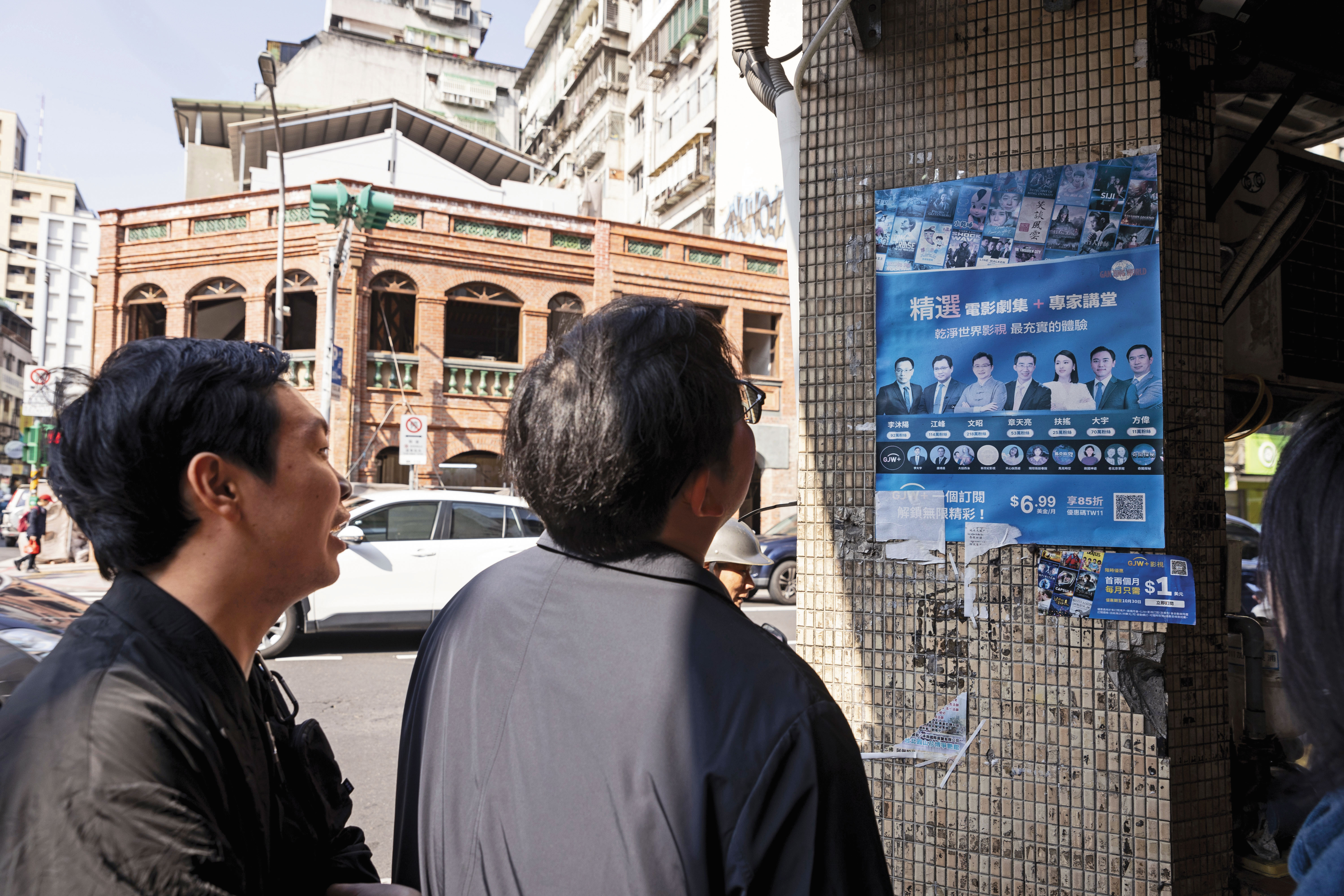 李穎（右）、多倫多方臉（左）訪台期間在街頭走動，無意看見牆面張貼斑駁的中國海外反共人士活動海報，2人駐足觀看許久。