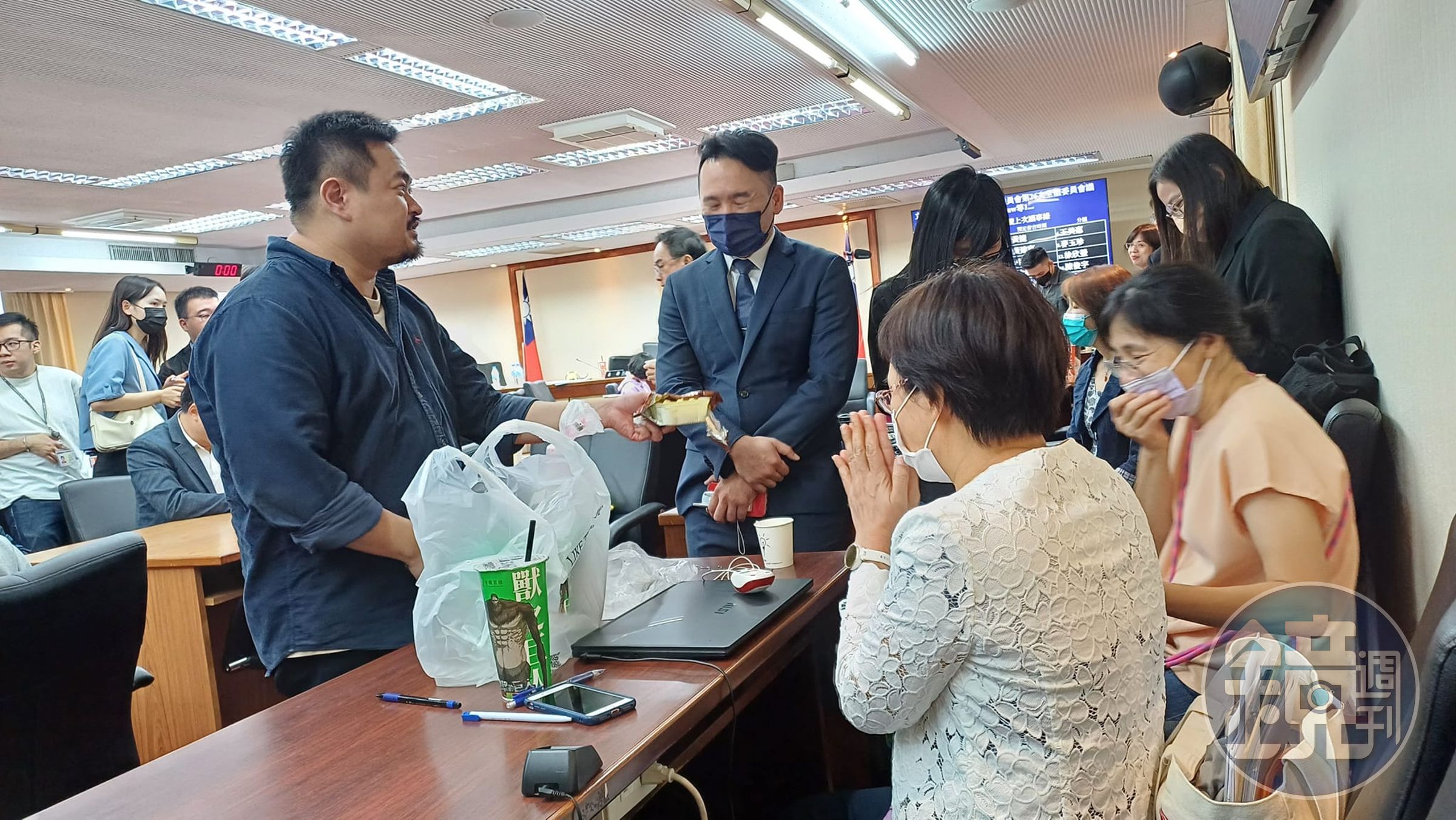 內政委員會議事人員無法離開會議室,綠委洪申翰遞上食物、飲料安撫。(讀者提供)