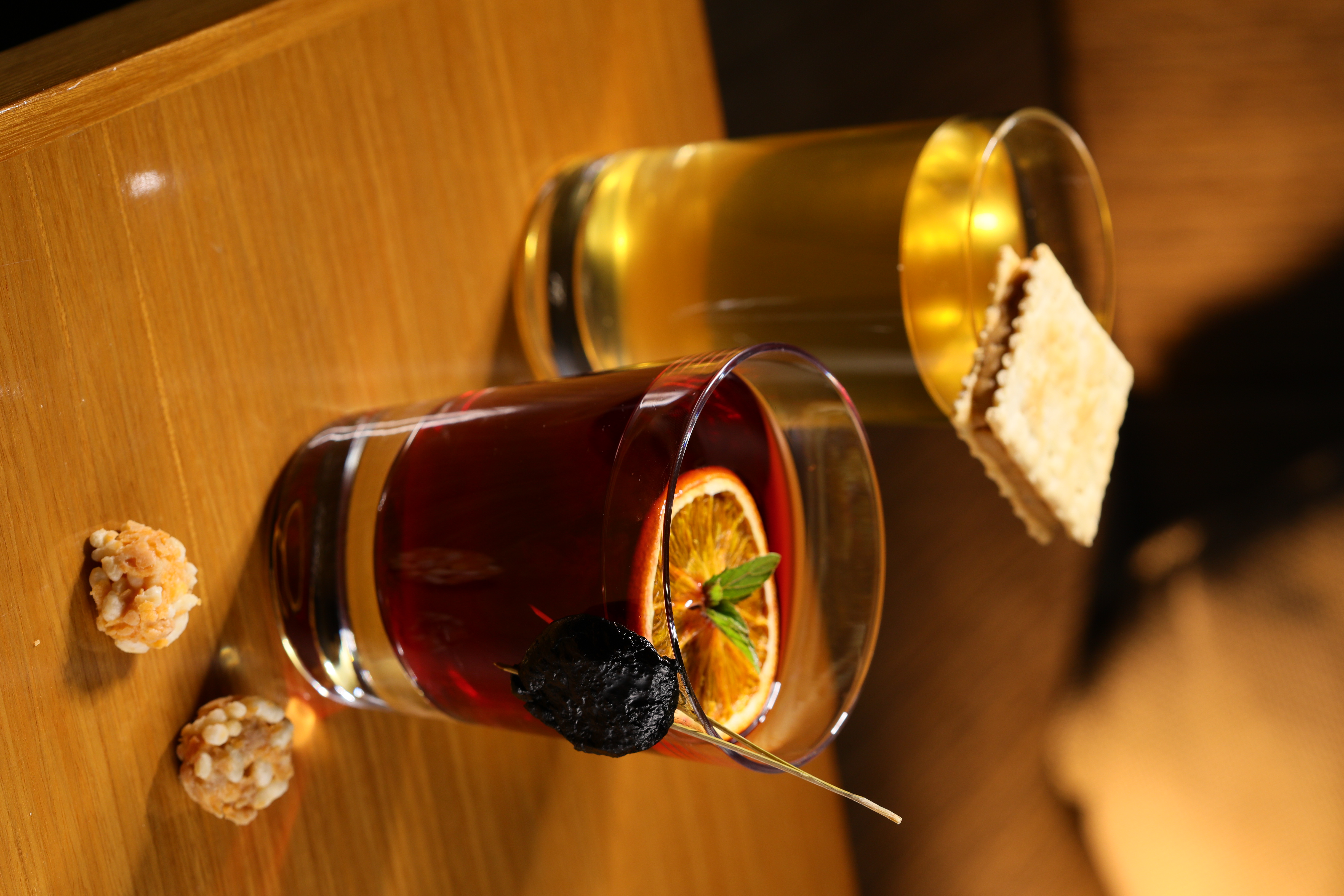 Bar Home的鹽味調飲「吾媽咪」（後），琴酒為基酒，添入少許鰹魚昆布高湯，並以虱目魚慕斯餅乾裝飾；「蜜語」（前）老台南人熟悉的傳統蜜餞化應子特調。