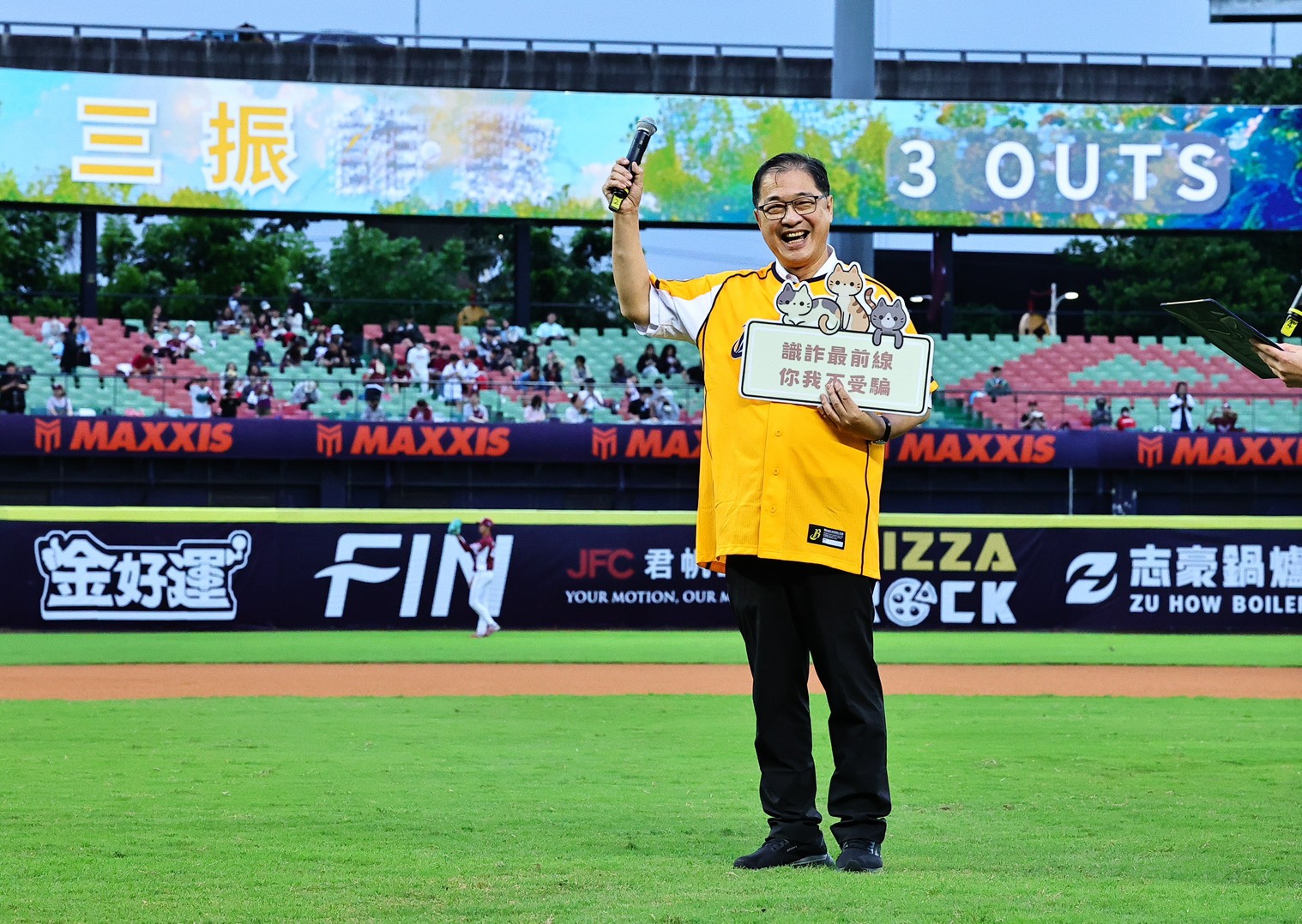 中信兄弟邀請法務部鄭銘謙部長到洲際球場宣導打詐反毒反賄選，手持標語「識詐最前線，你我不受騙」。（中信兄弟提供）